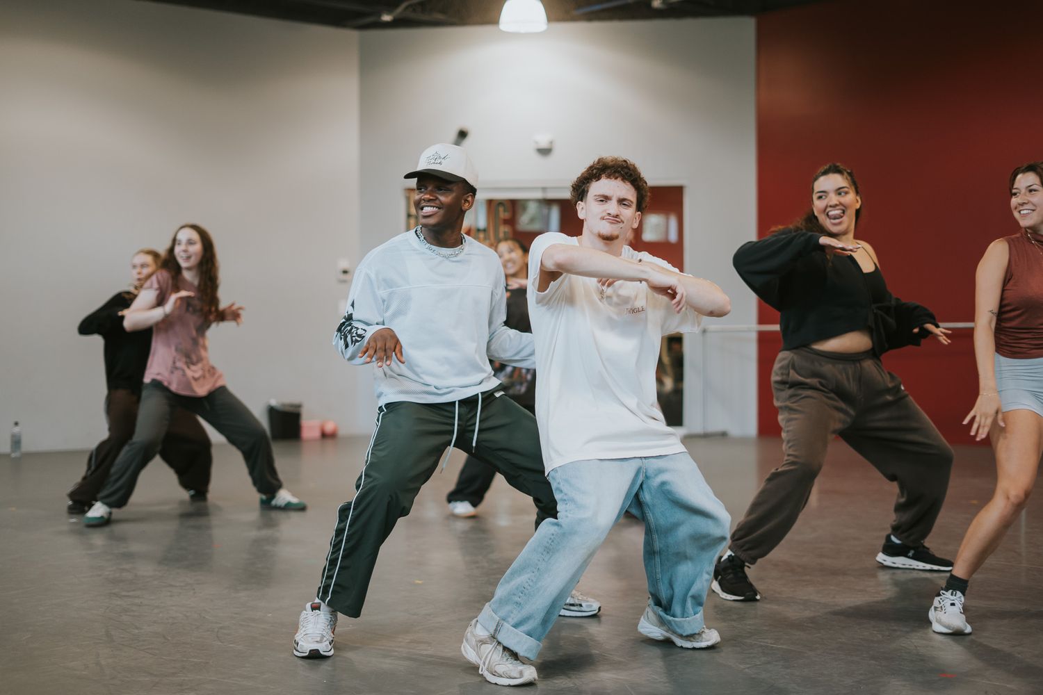 A group performs synchronized hip-hop dance moves in a modern studio space.