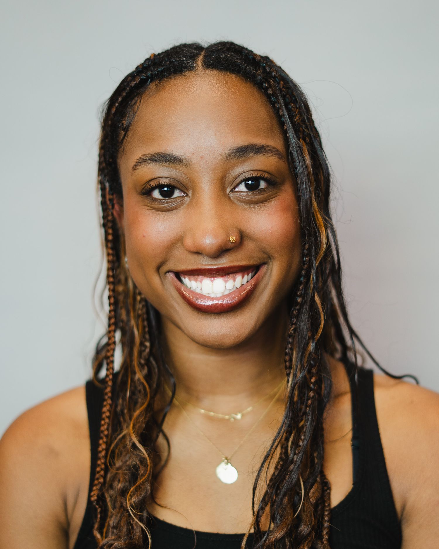 Portrait series featuring braided hairstyle and bright smile against grey backdrop.
