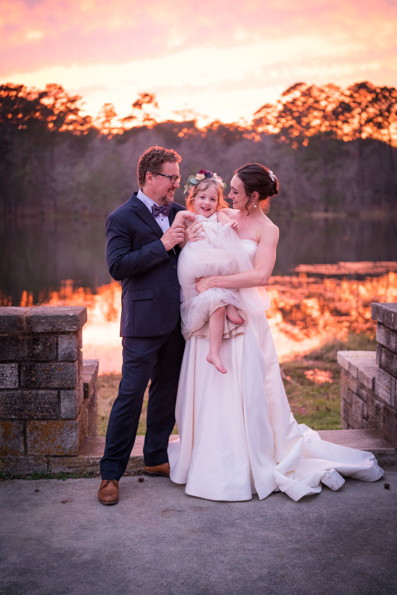 Wedding party photos captured at sunset against a waterfront stone backdrop.