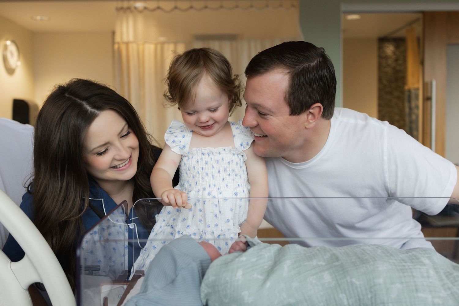 A happy family shares tender moments together while lounging on a light-colored couch in their home.