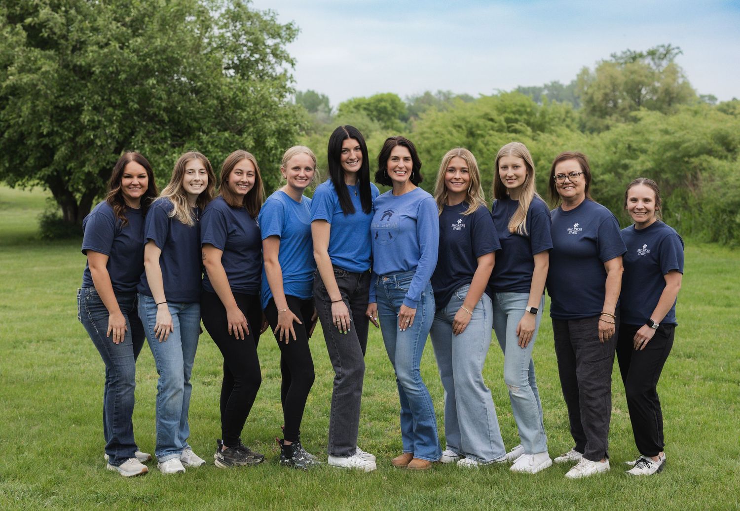A group of people wearing coordinated blue and black outfits standing together in a grassy field for a photo.