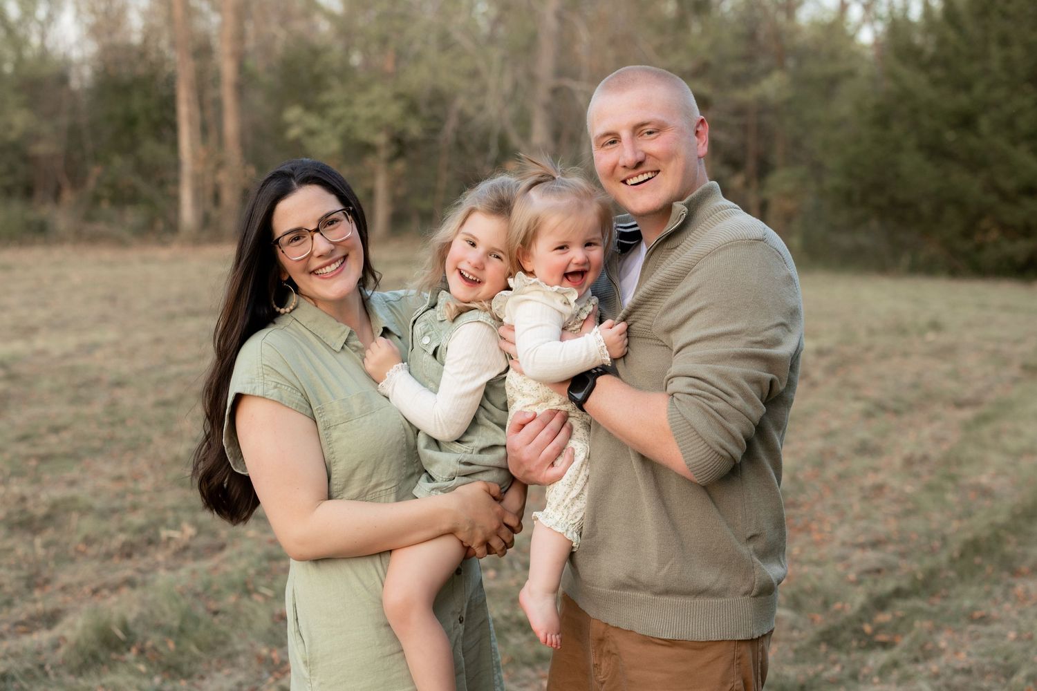 A family poses together outdoors in a natural setting during a golden hour photo session.