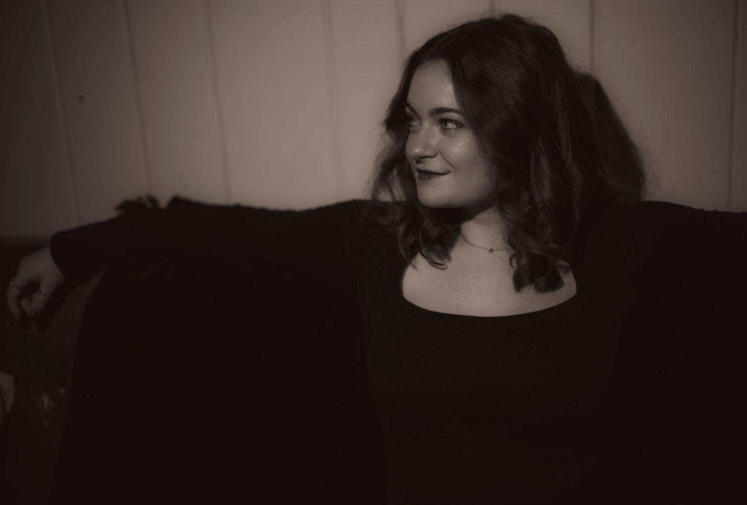 A black and white photo of a girl sitting on the couch