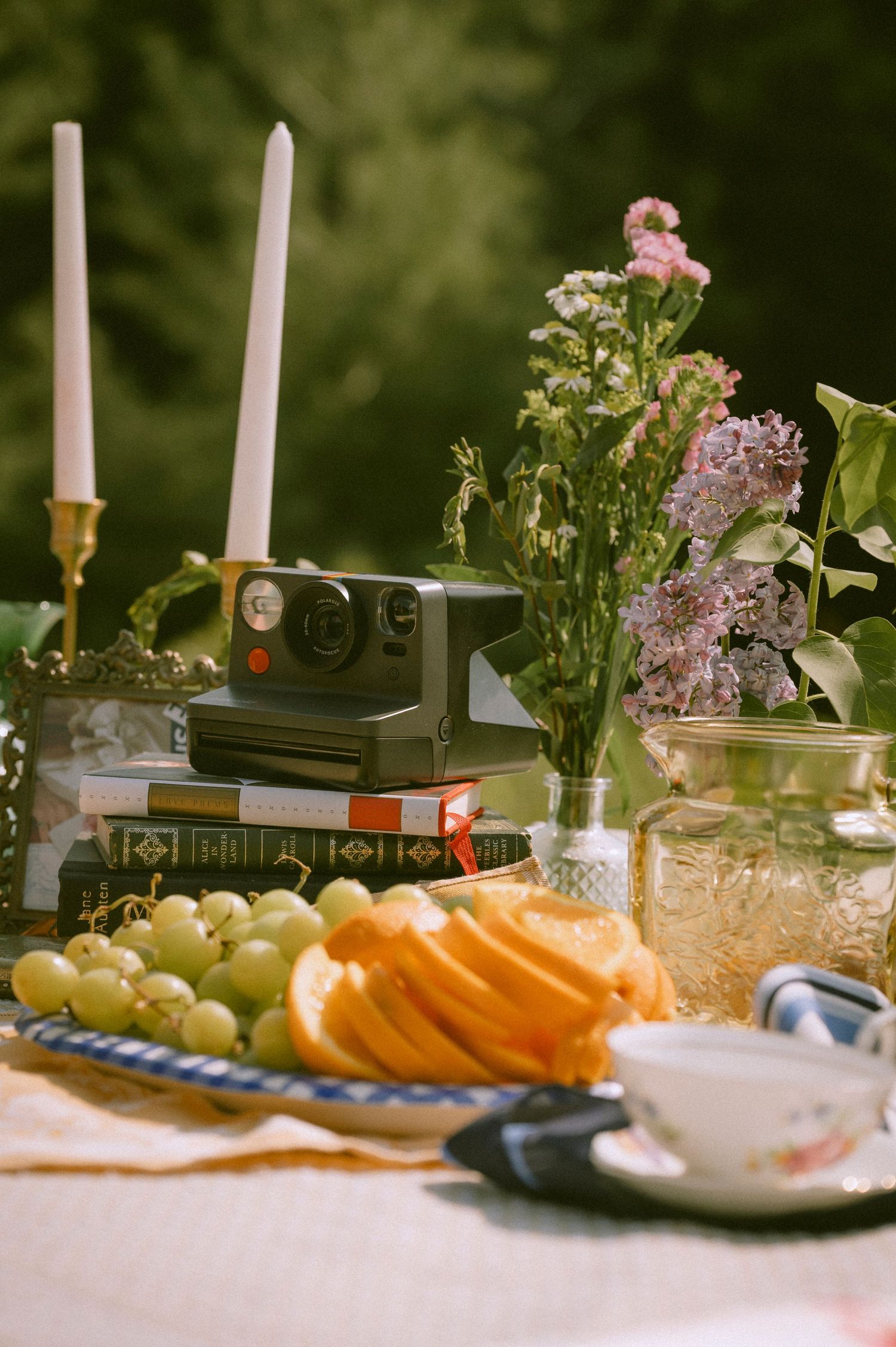 A detail shot of fruits and candle sticks with pink flowers and an old Polaroid camera
