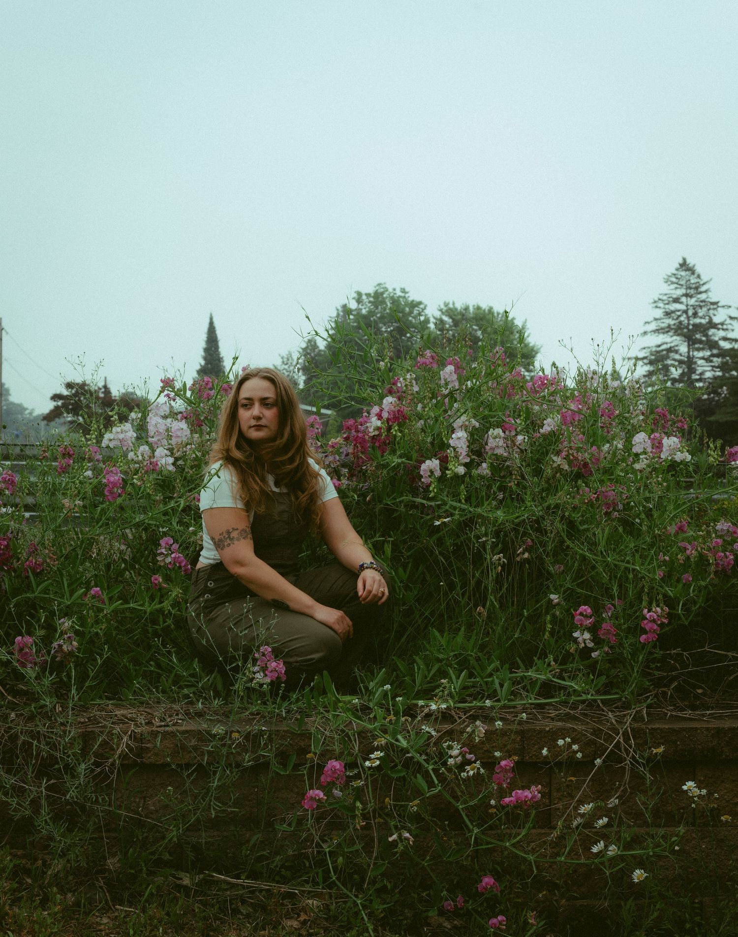A girl kneels in front of pink and white wildflowers