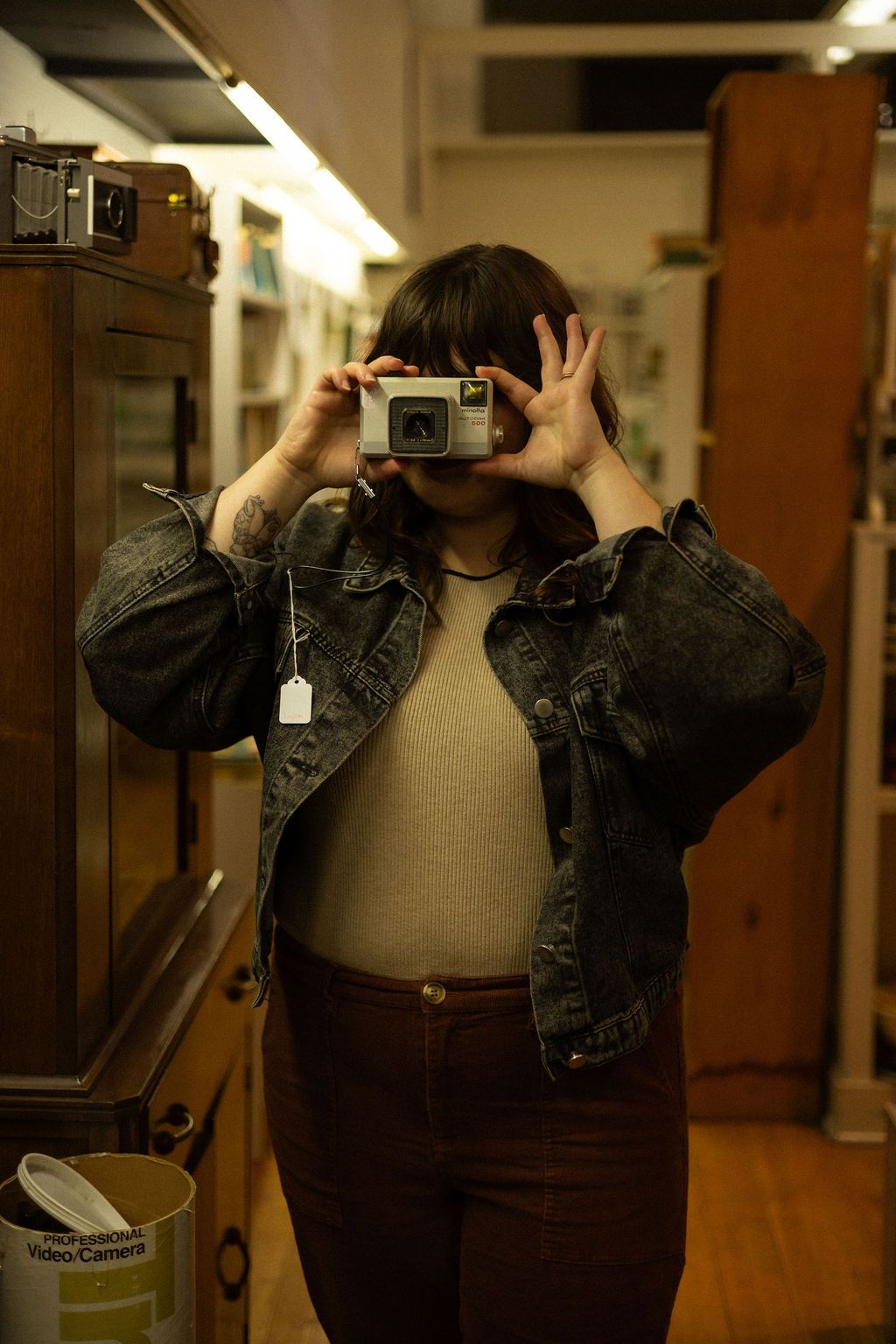 A women holds an old camera to her face in a thrift store