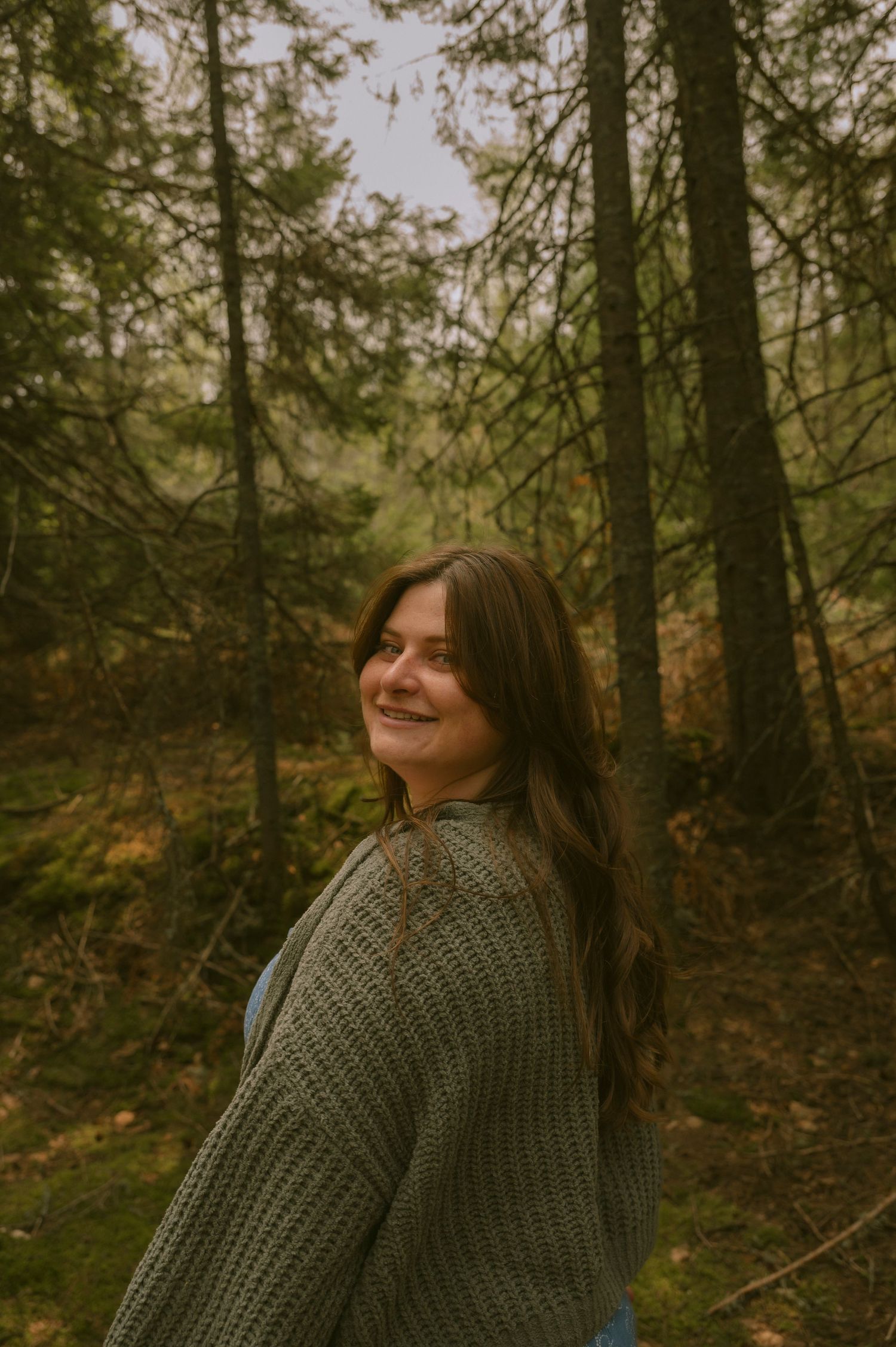 A photo of a woman looking over her shoulder in a cedar forest