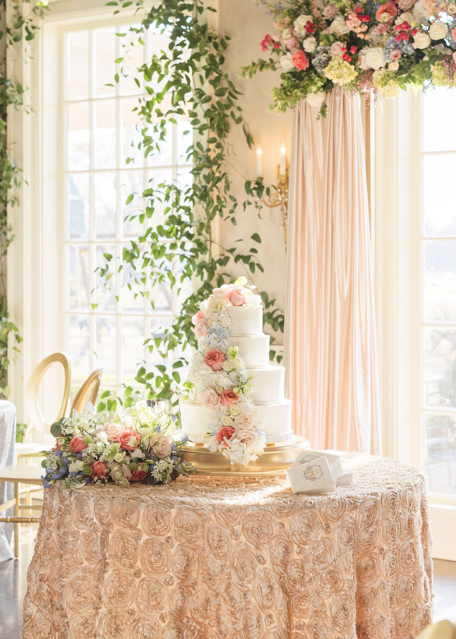 Wedding reception table with floral arrangements, blush linens and romantic window lighting.