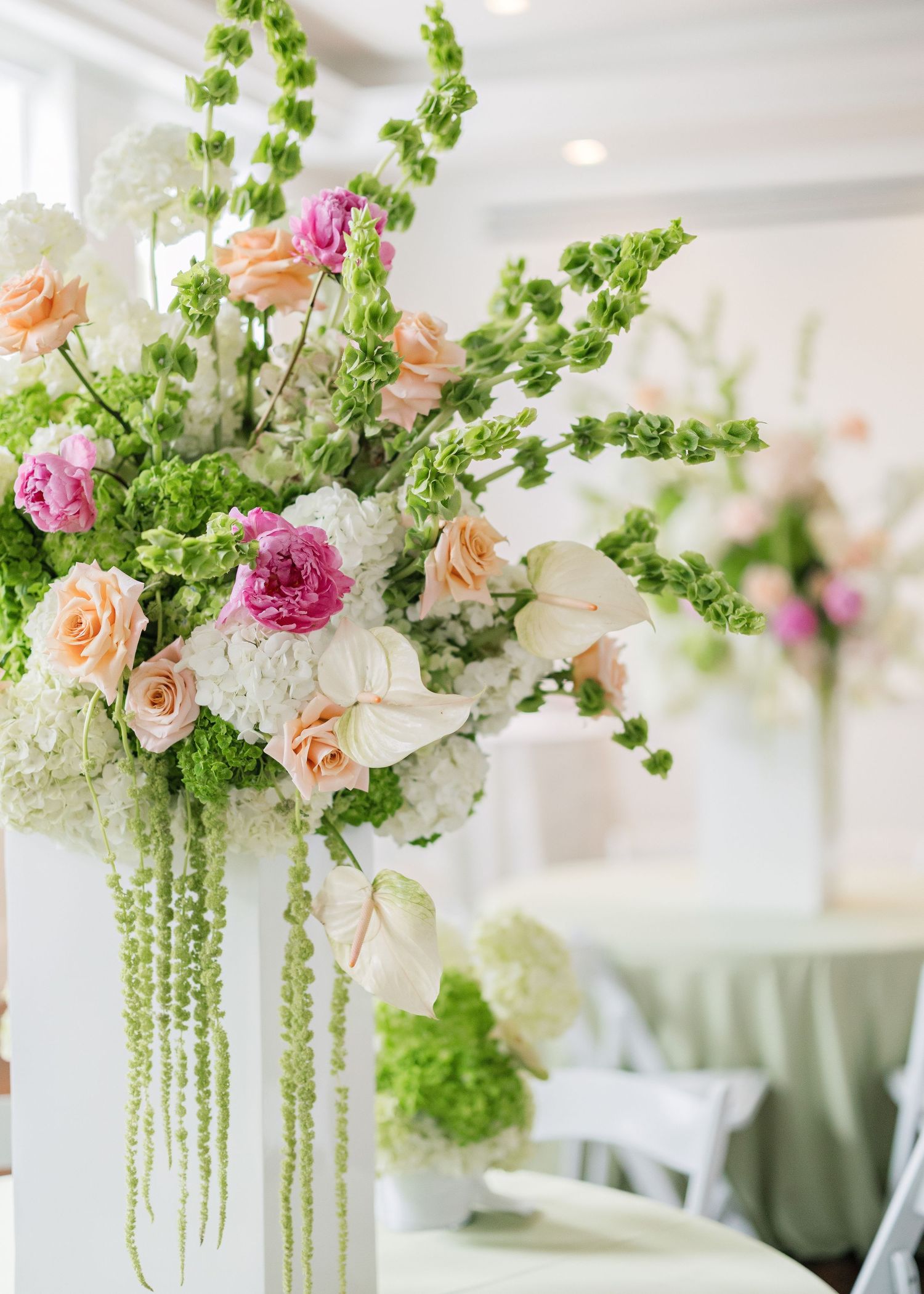 Sophisticated floral arrangement with pink roses and cascading greenery in white vase.