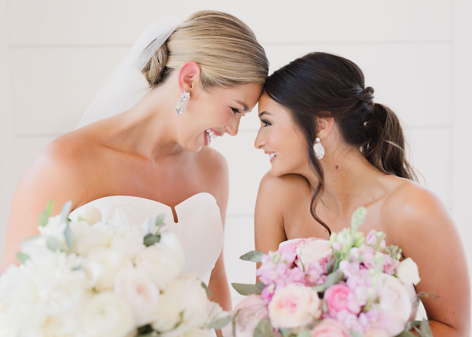 Wedding couple shares intimate moments with soft white and pink floral arrangements.