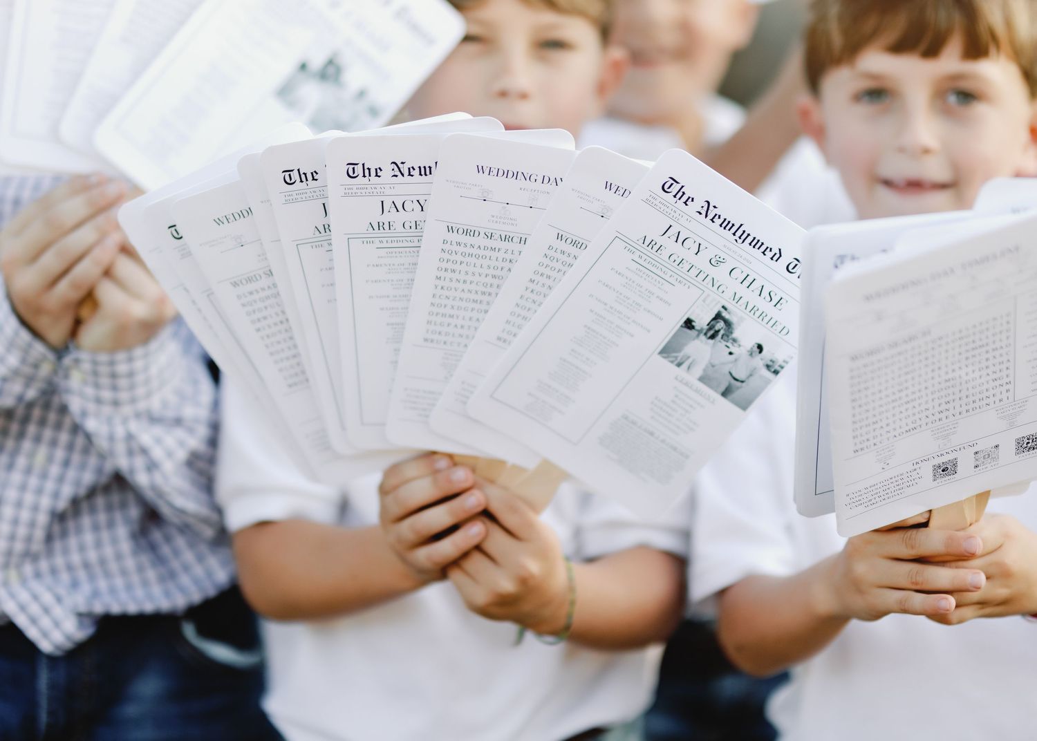 Young children holding and reading from white paper programs or menus.