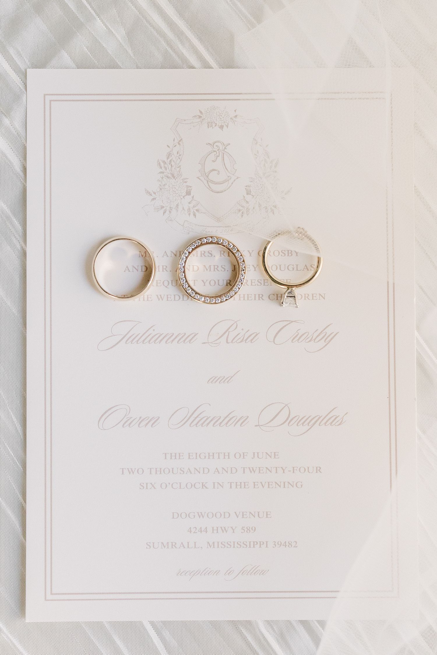 Wedding rings and elegant white wedding invitations with delicate calligraphy.