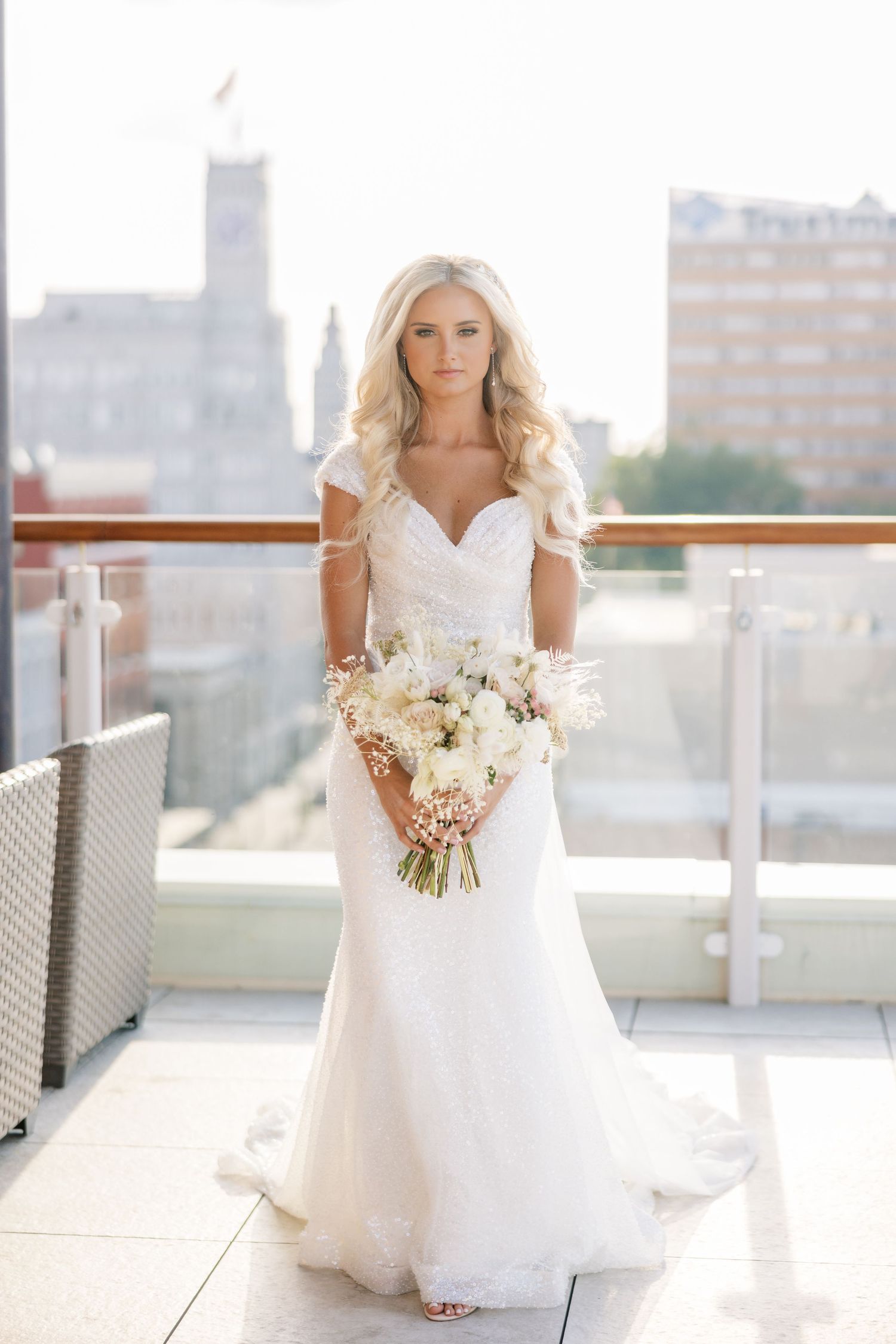 Elegant white wedding dress with sweetheart neckline and neutral bouquet photographed on urban rooftop terrace.