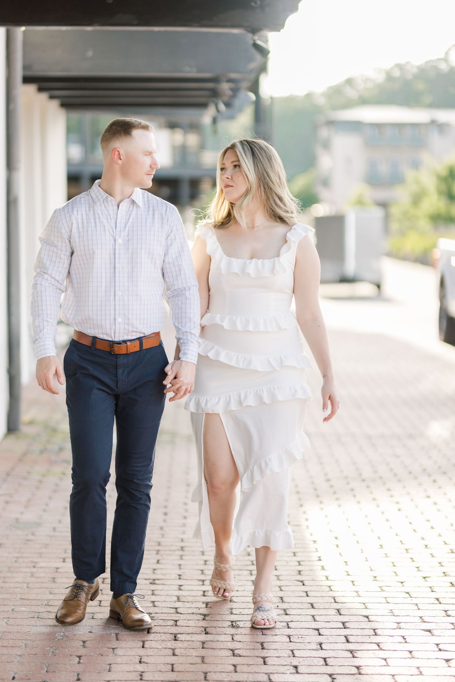Couple walking together on brick pavement, wearing coordinated white and navy blue outfits.