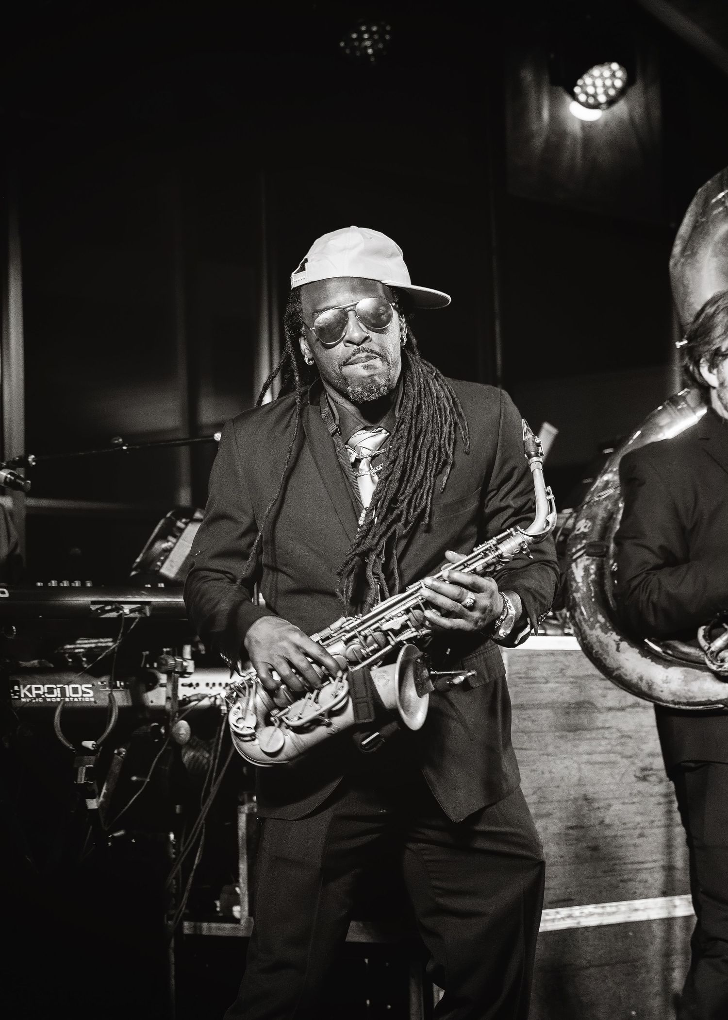 A black and white photo series shows musicians performing with saxophones and guitars on a dimly lit stage.
