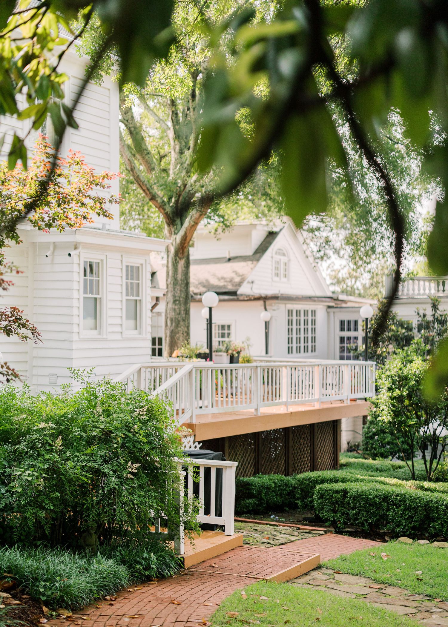 White farmhouse style venue with wooden deck and lush green landscaping.