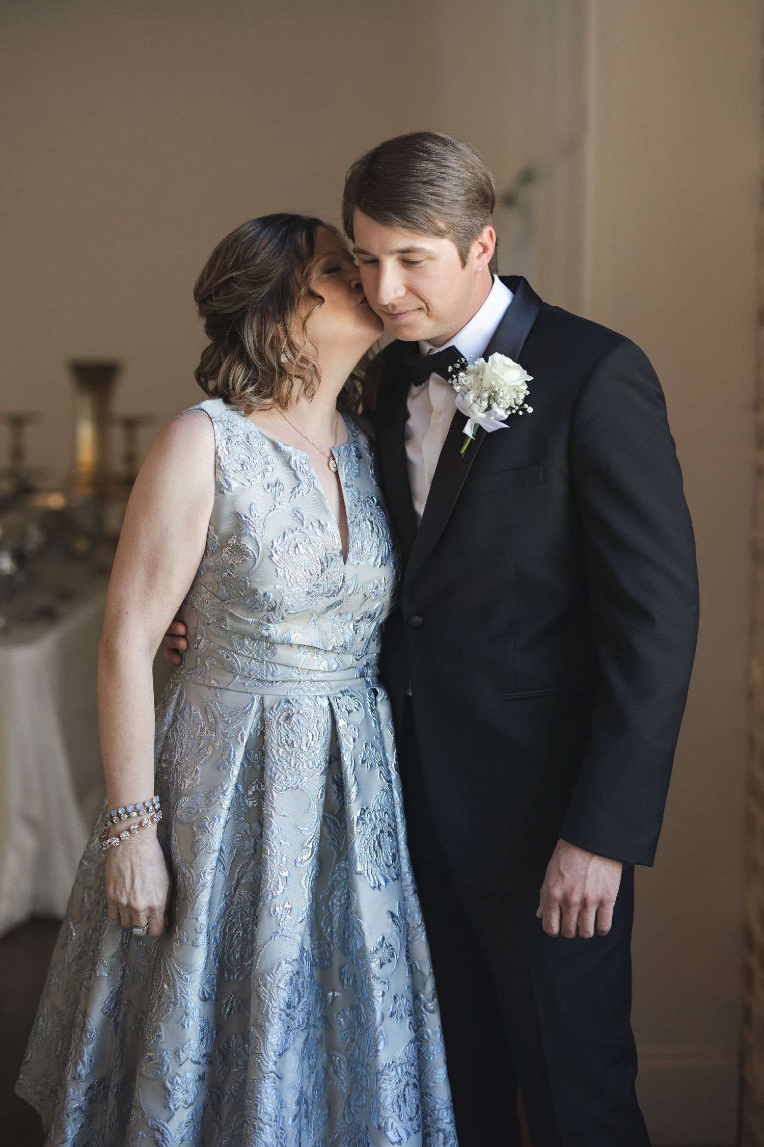 Couple shares tender moment in formal attire with light blue lace dress.