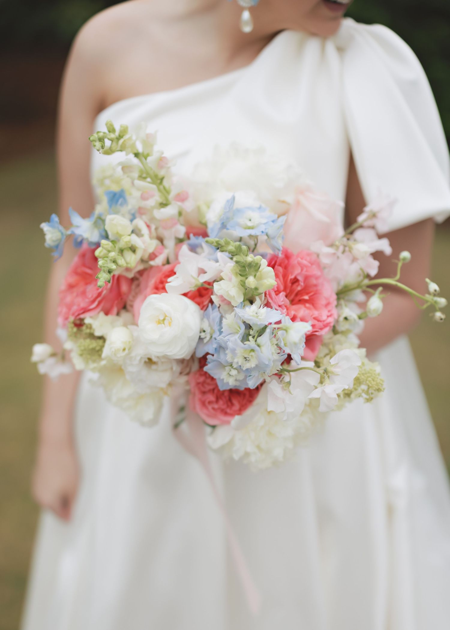 Romantic pastel bouquet featuring coral, blue and white flowers with delicate greenery.