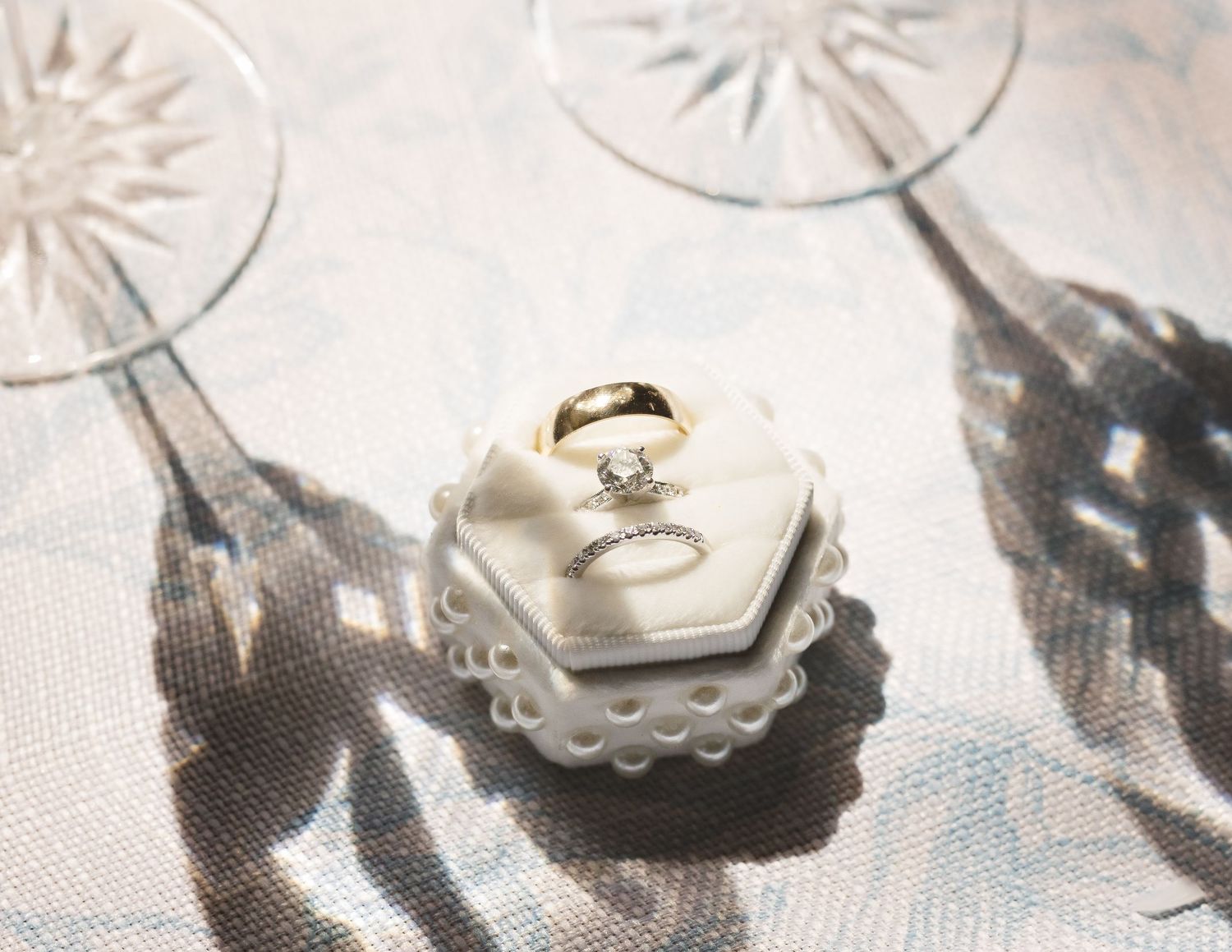 Wedding rings casting dramatic shadows on white textured surface.