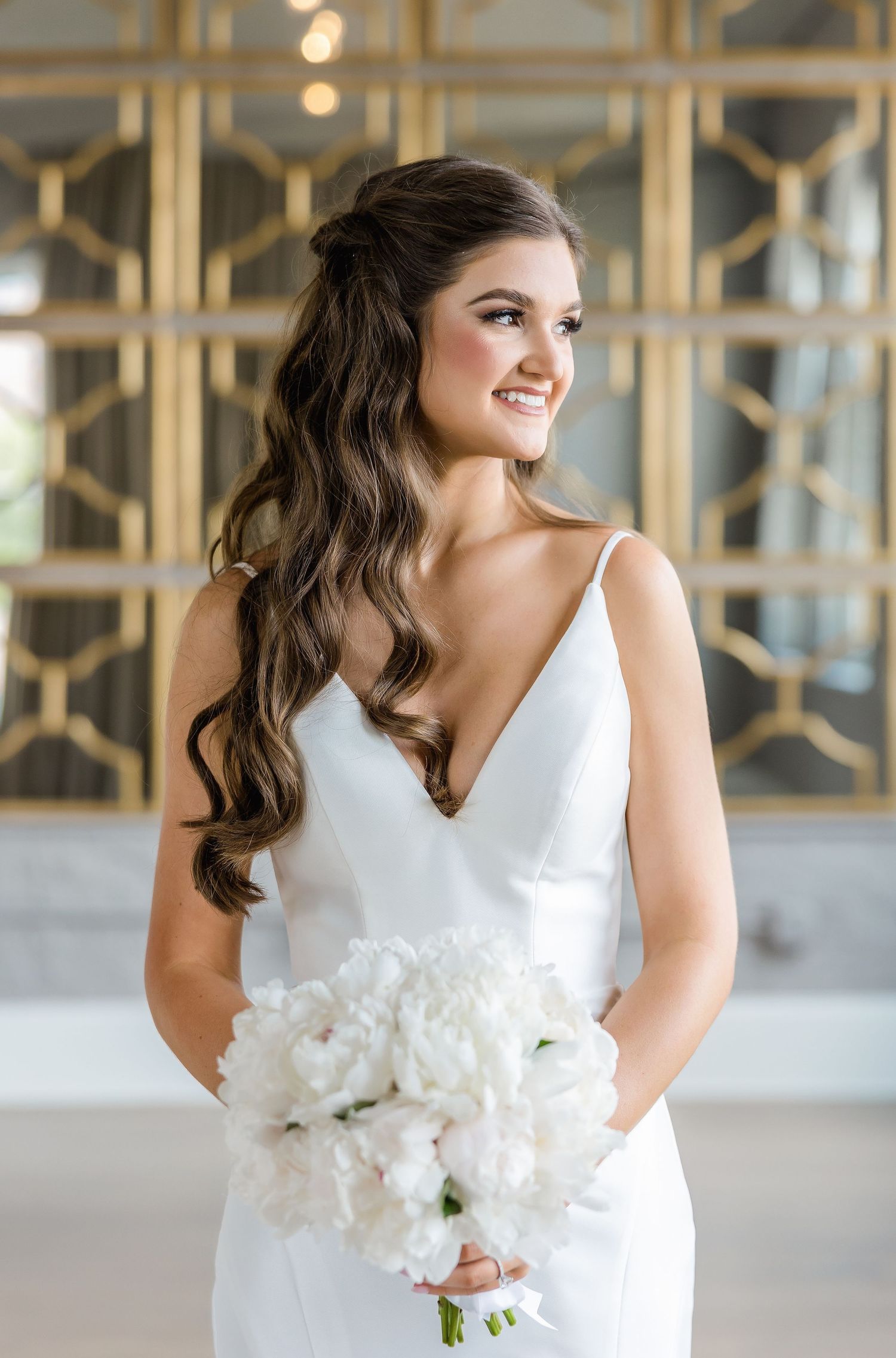 Elegant bouquet of pure white peonies being held against a white wedding dress.