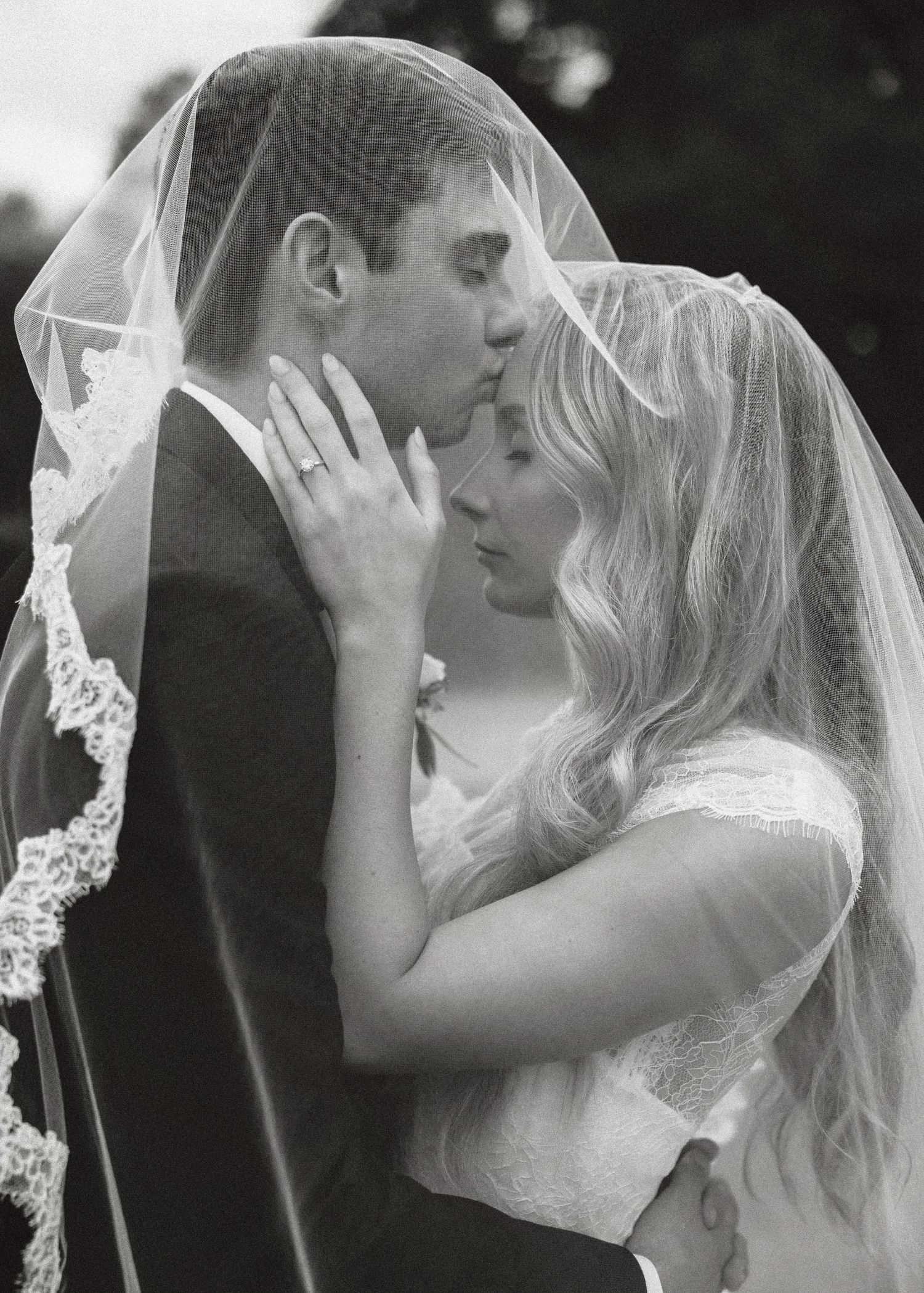 Black and white photo sequence showing a romantic kiss between a bride and groom under a delicate lace veil.