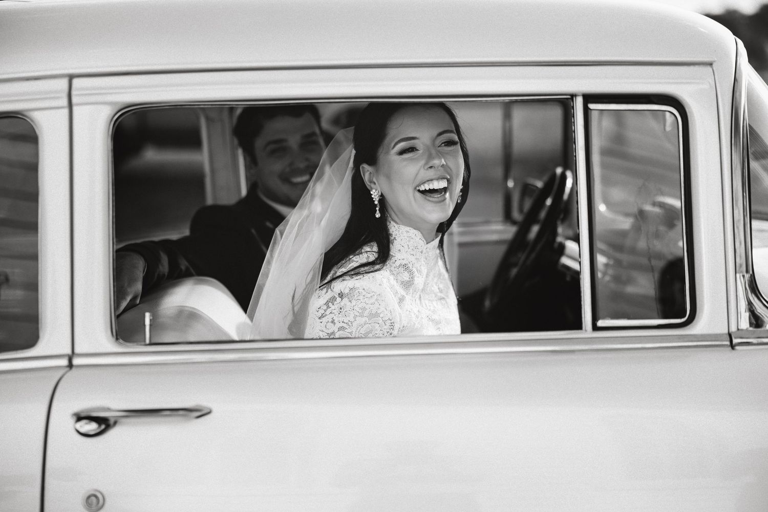 Classic wedding photos of a bride in a vintage car through black and white photography.
