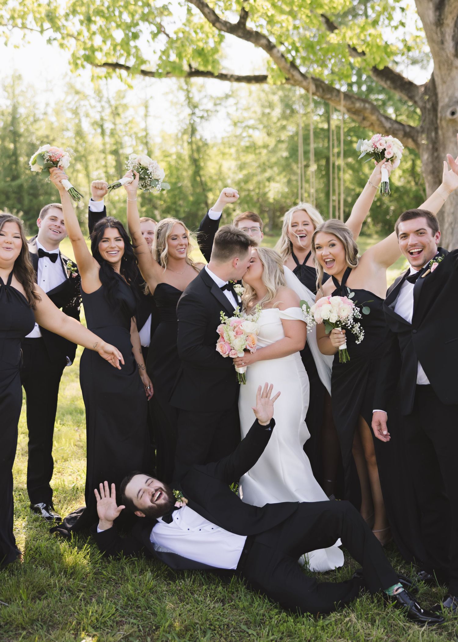 Wedding party in black and white attire poses playfully in a series of outdoor photos with trees in background.