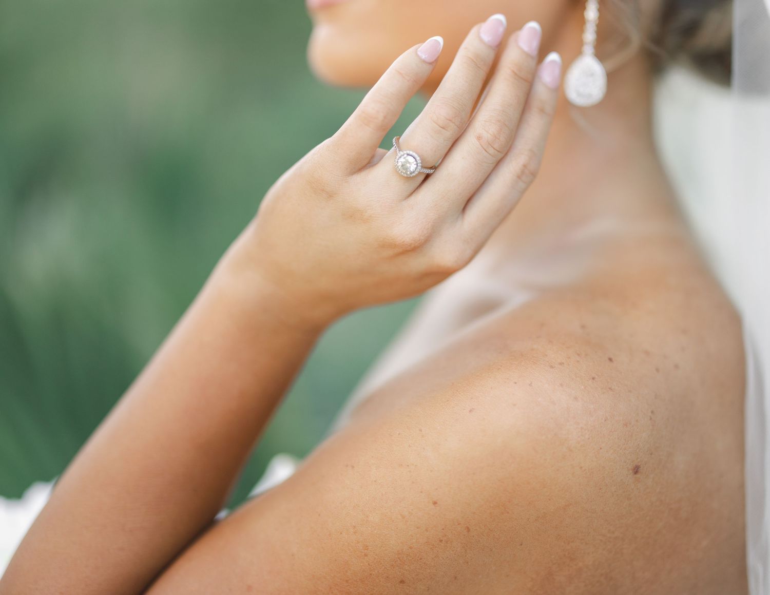 Close-up of an engagement ring being shown on a woman's hand against a soft blurred background.