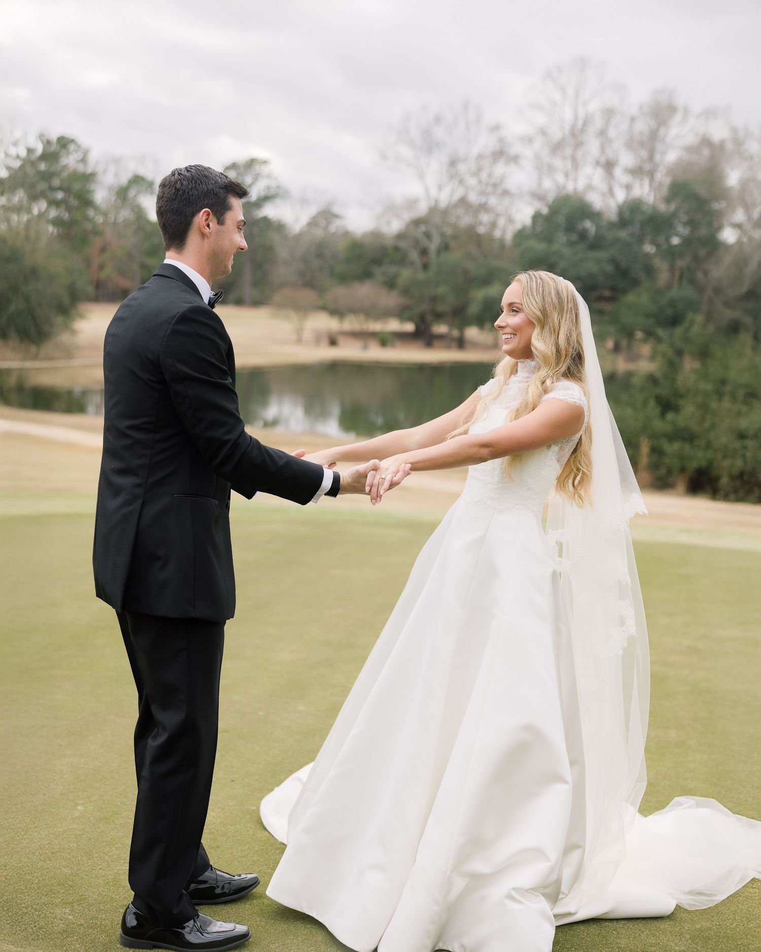 A couple in wedding attire dance and twirl together on a lush green golf course during their special day.