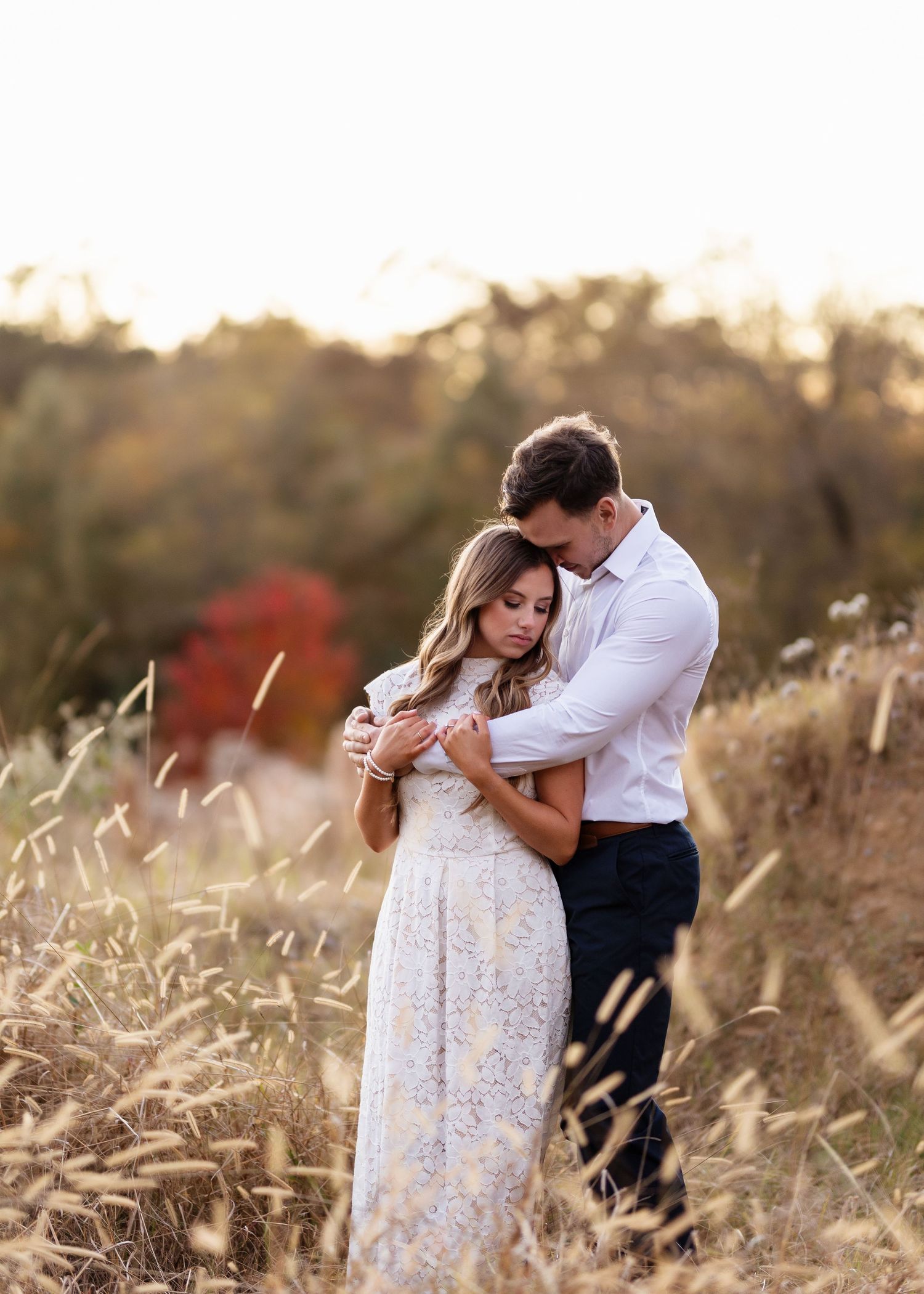 Sweet candid moments captured in tall grass during sunset photoshoot.