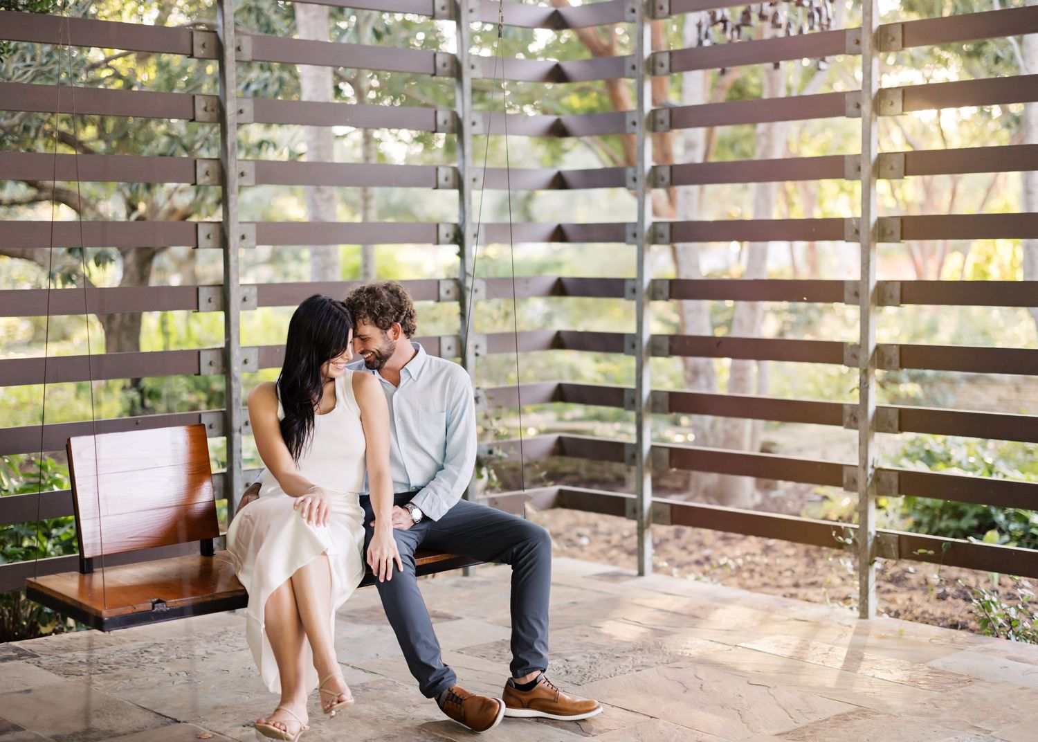 Intimate photoshoot on wooden bench with rustic fence backdrop.