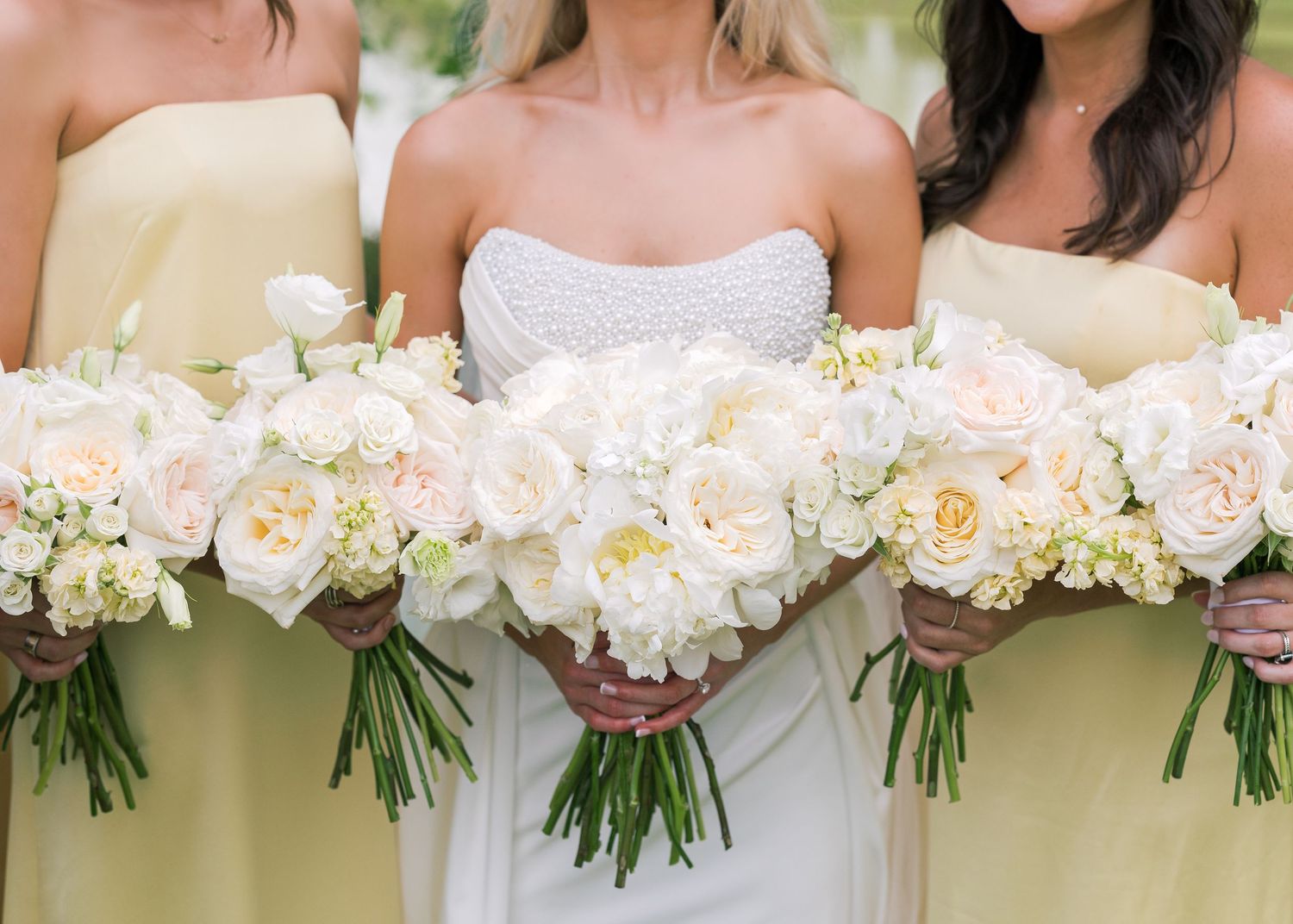 Row of bridesmaids holding white and blush pink wedding bouquets.