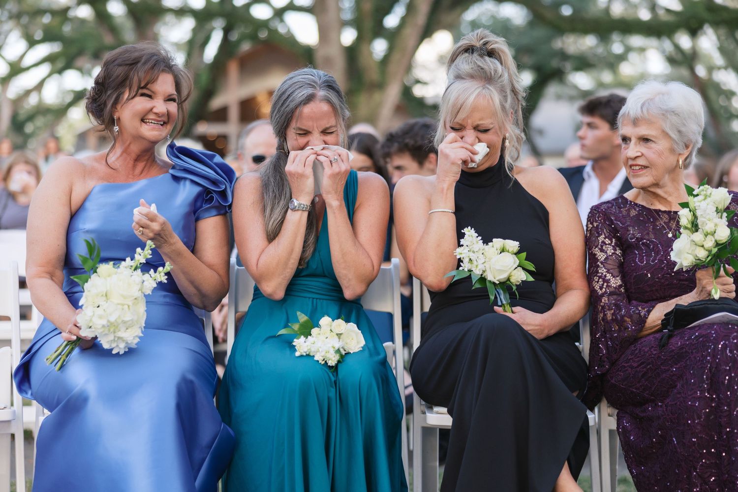 Wedding party reacting emotionally in coordinated blue and purple dresses.