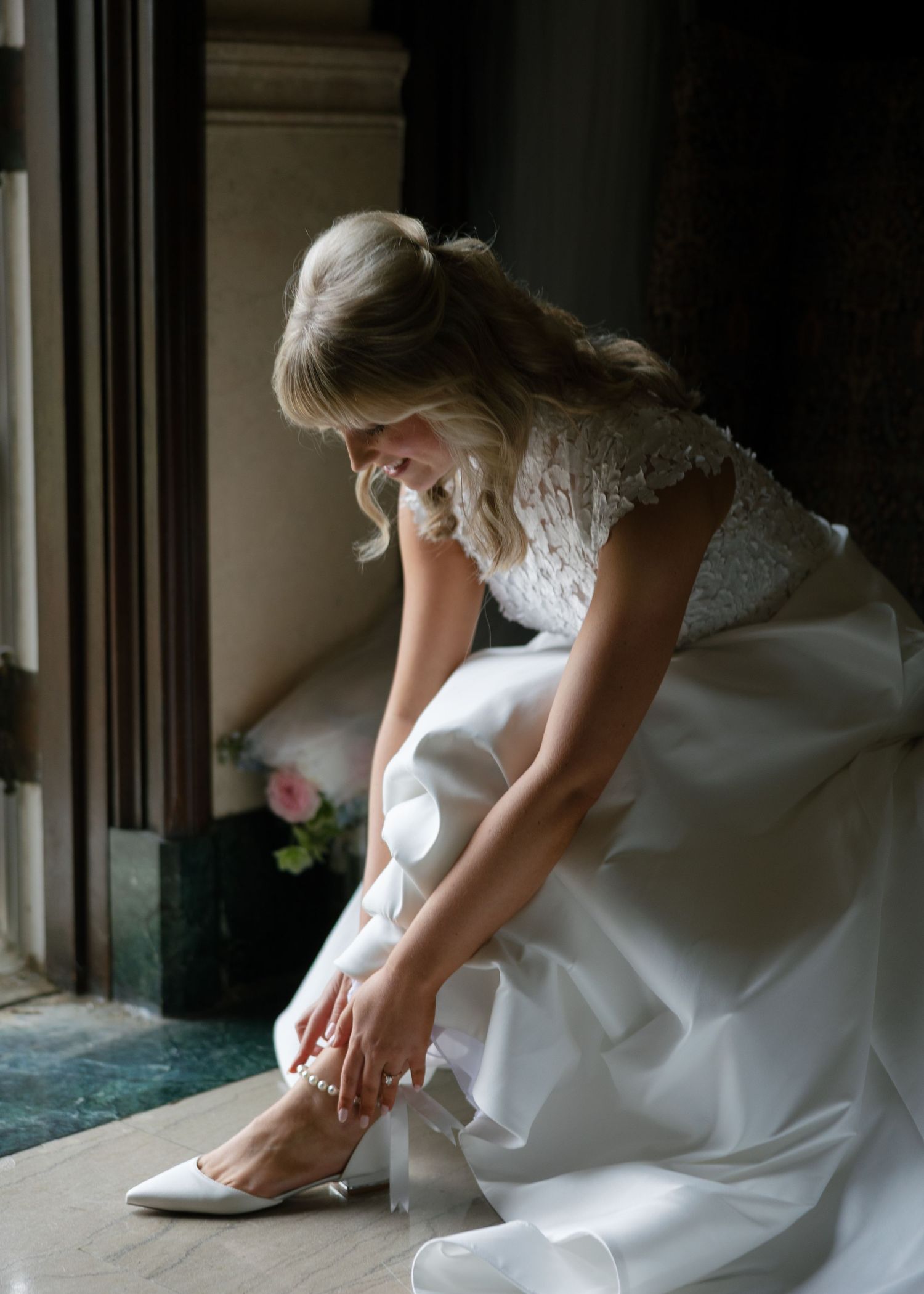 Close-up shot of bride adjusting her white wedding shoes.
