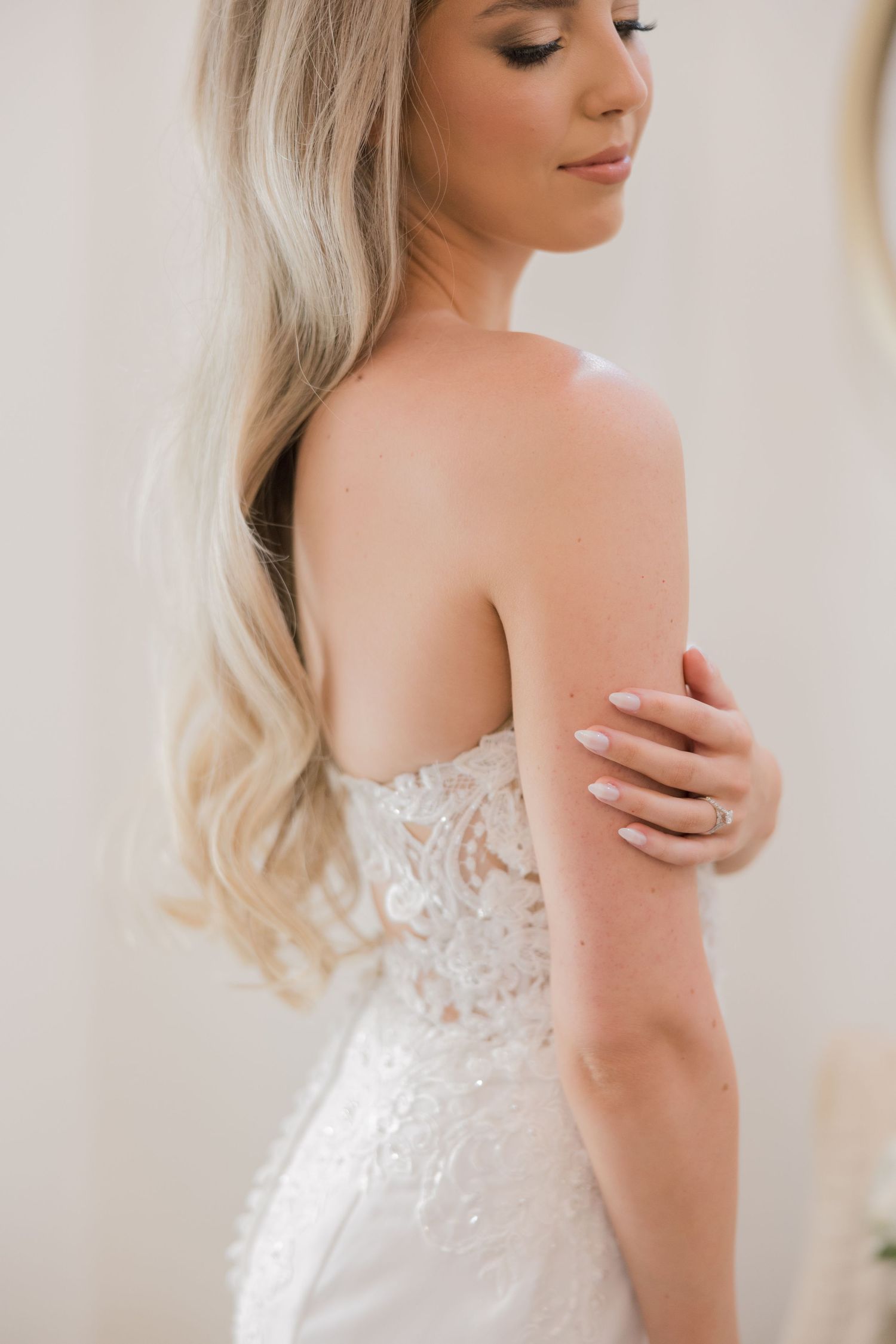 Close-up views of a strapless white lace wedding dress with delicate beading detail and plunging back design.