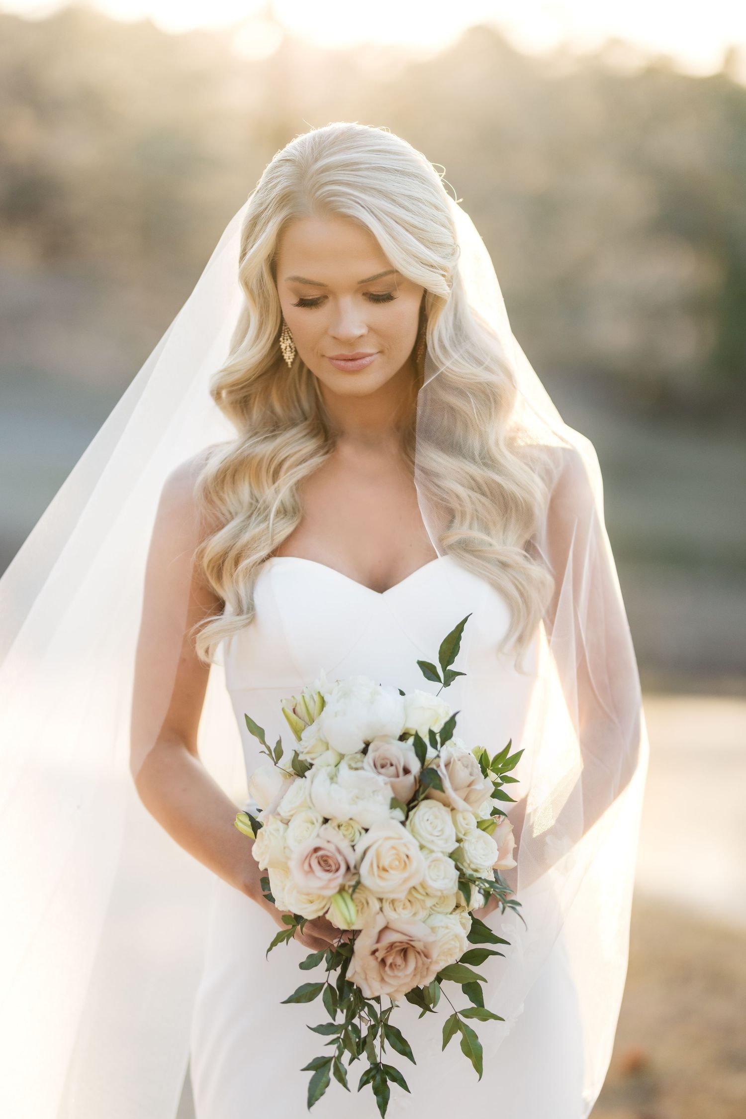 Ethereal bridal portraits in soft sunlight featuring a sweetheart neckline gown and white rose bouquet with greenery.