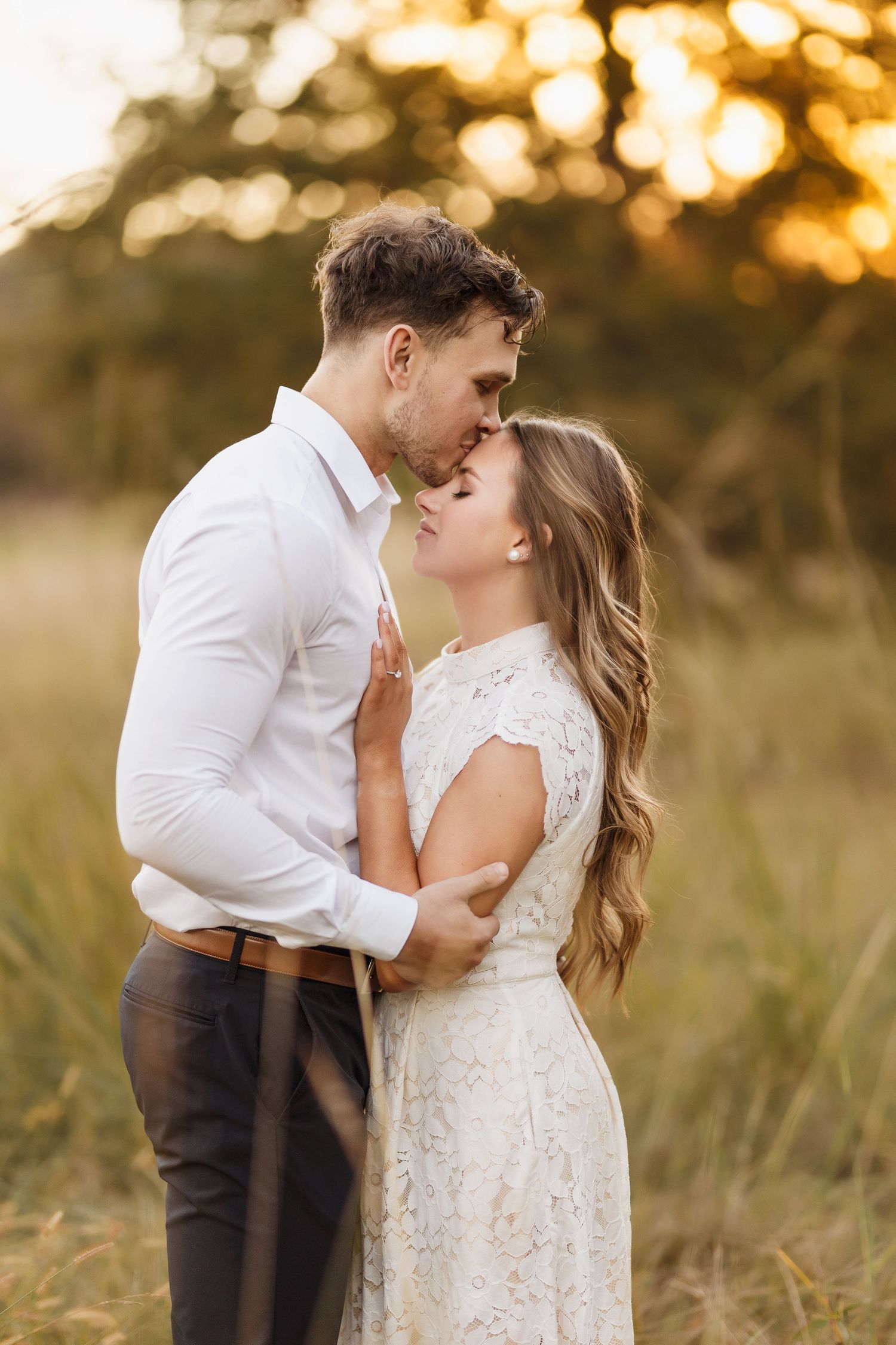 Intimate couple poses during sunset in a field wearing formal wedding attire.