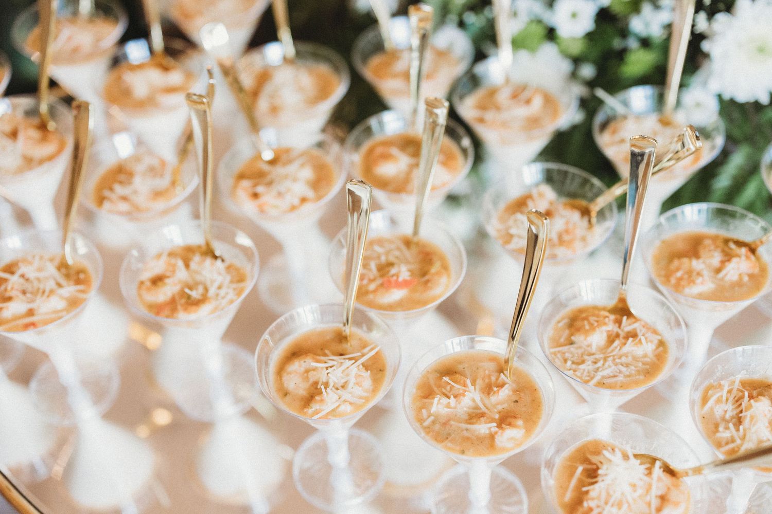 Multiple champagne glasses filled with peach-colored cocktails arranged on serving tray.