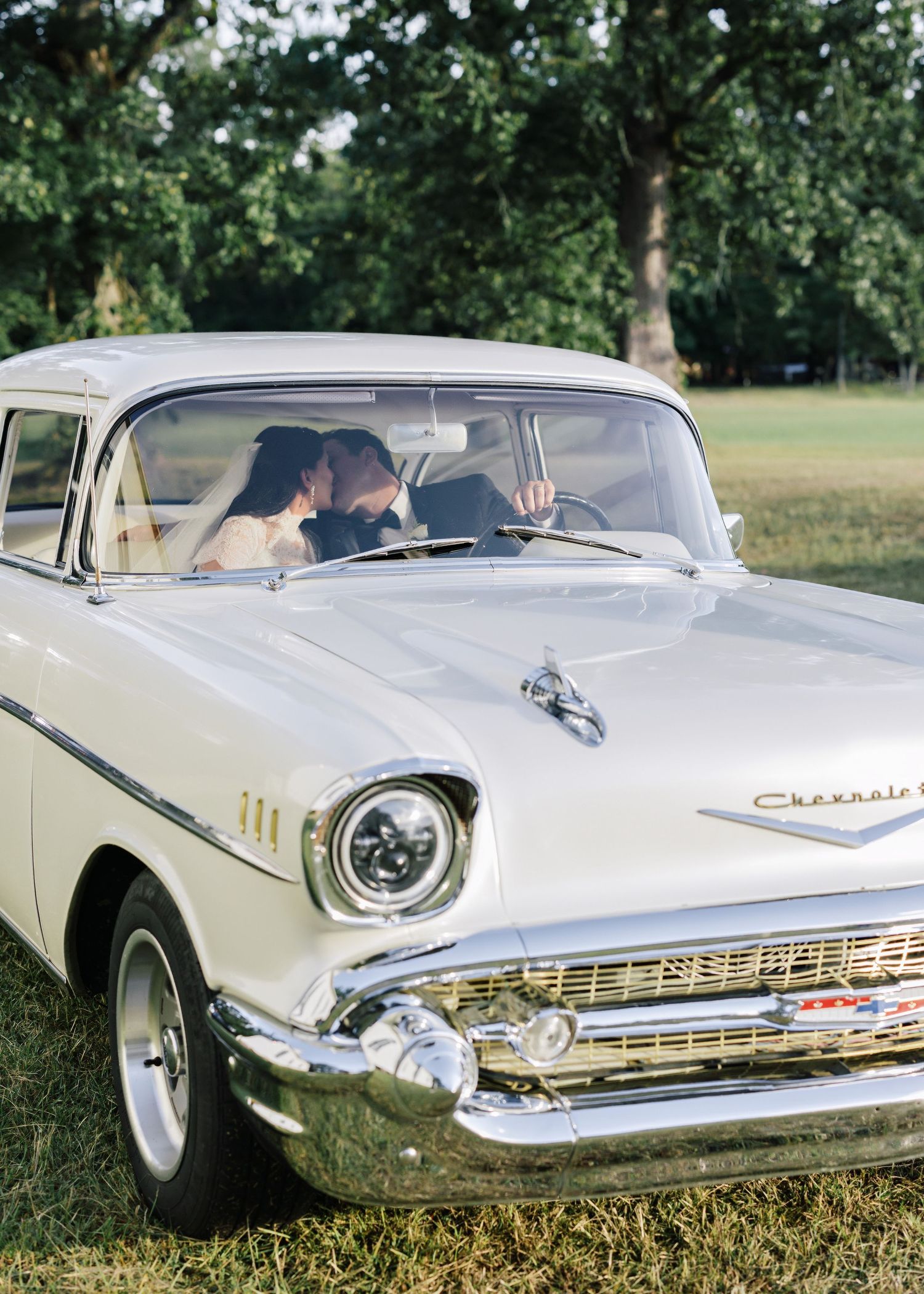 Classic white Chevrolet car details showing chrome trim and front grille in an outdoor setting.