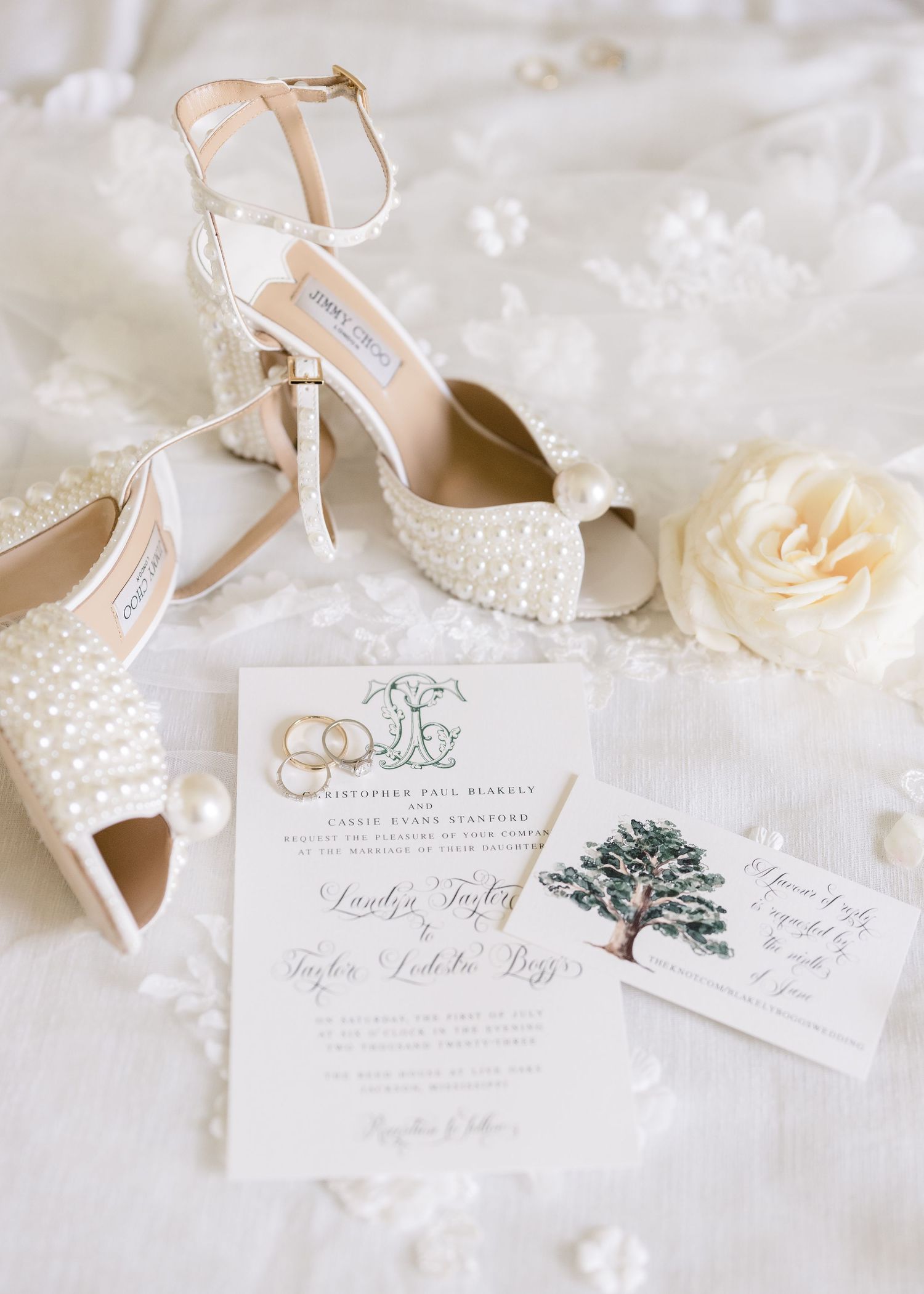 Elegant wedding details including pearl-adorned shoes, white floral invitation suite, and delicate lace accents.