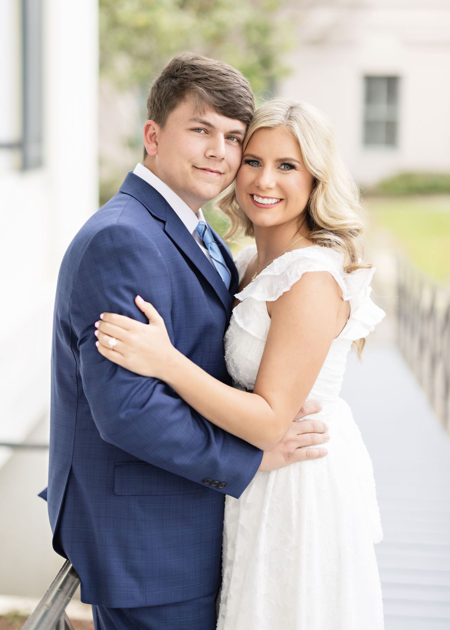 Formal portrait of a couple in navy suit and white dress.