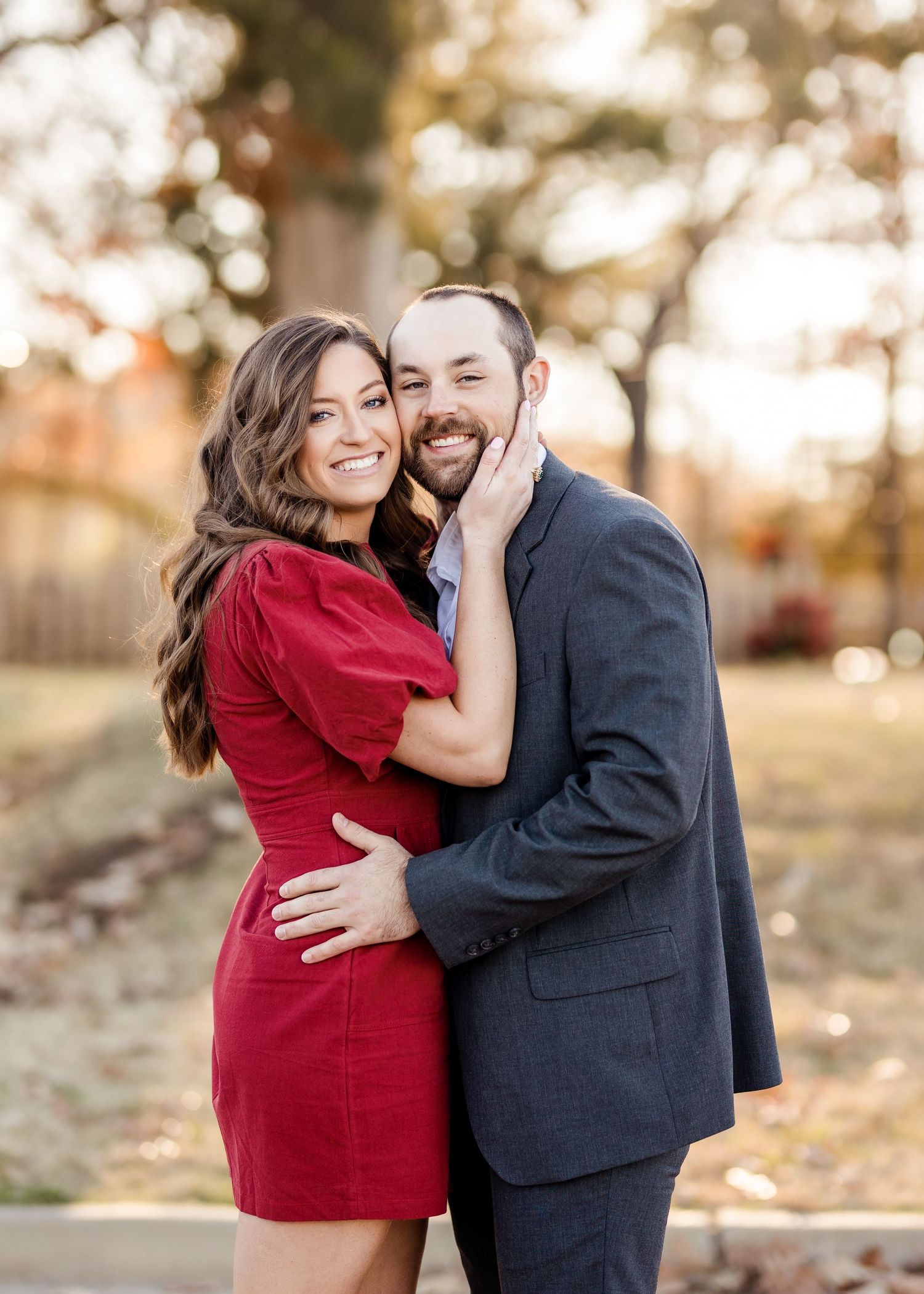 Romantic couple sharing tender moments in autumnal setting wearing red and navy outfits.