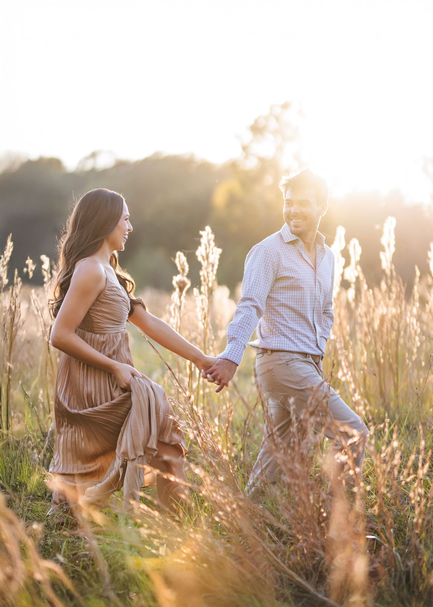 Silhouettes of people walking through tall grass at golden sunset.