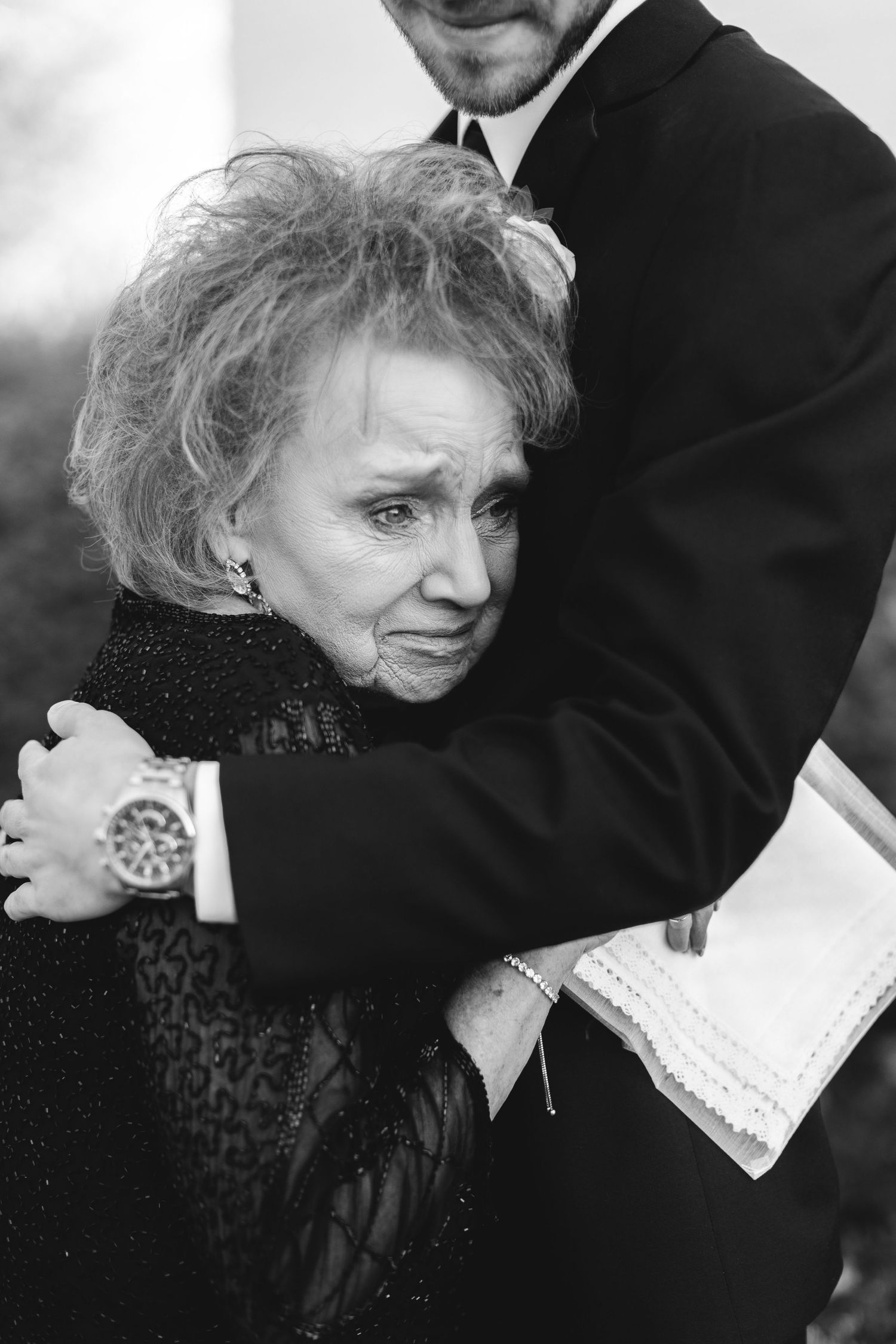 Black and white photo of an emotional embrace at a formal event.
