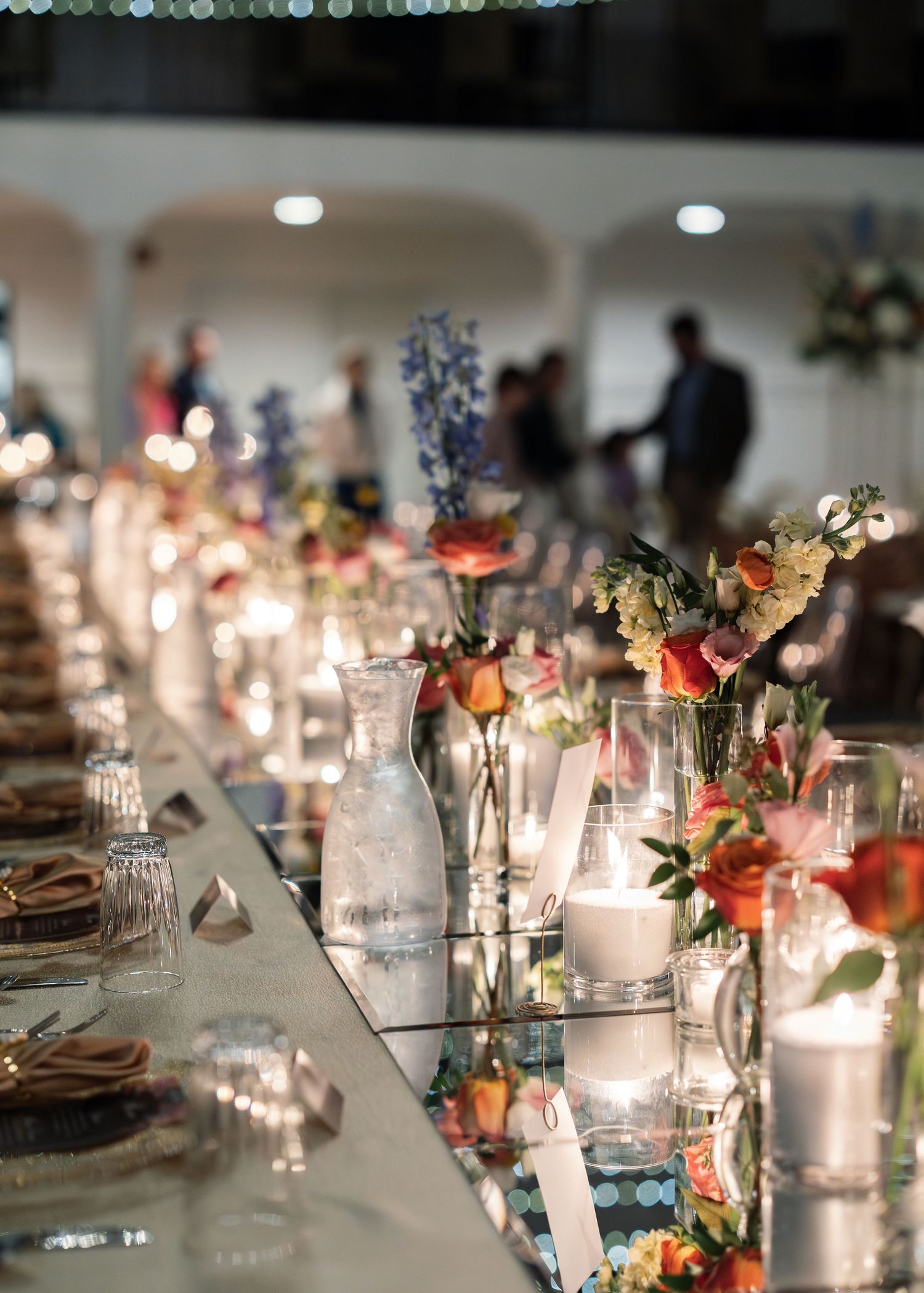 A romantic wedding reception table decorated with glowing candles, delicate floral arrangements, and elegant glassware.