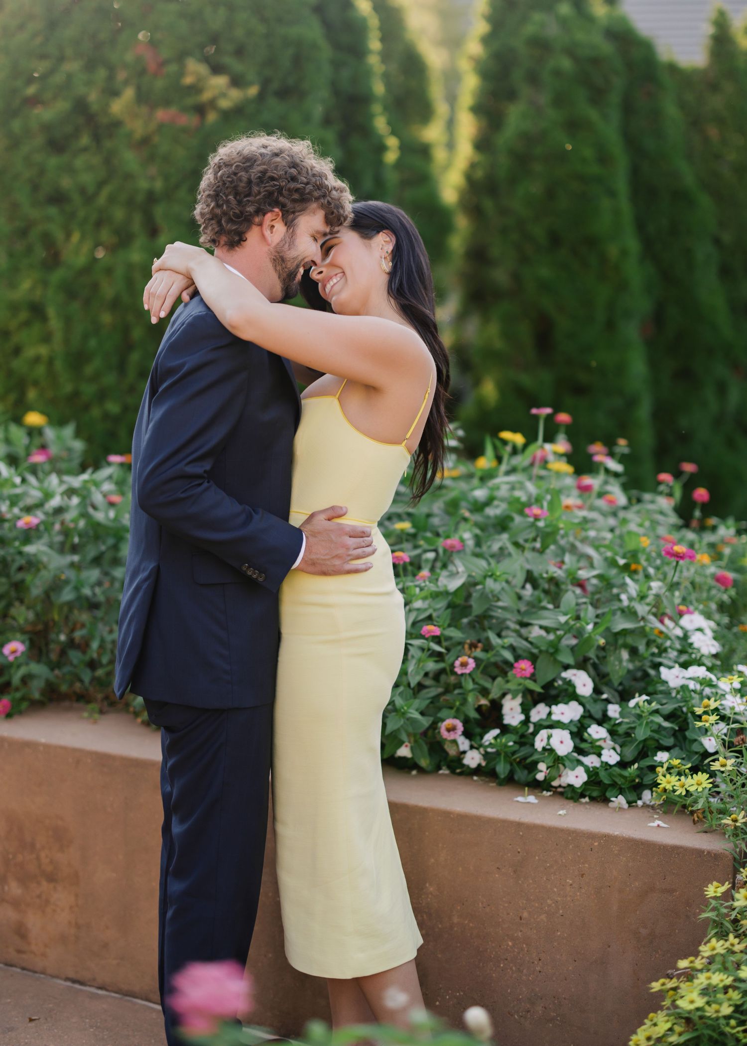 Couple shares tender moments in a garden with colorful flowers and greenery.
