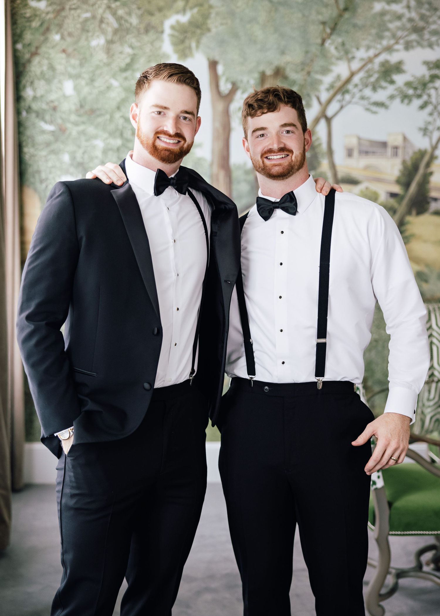 Groomsmen in black tuxedos and bow ties pose together for wedding photos.