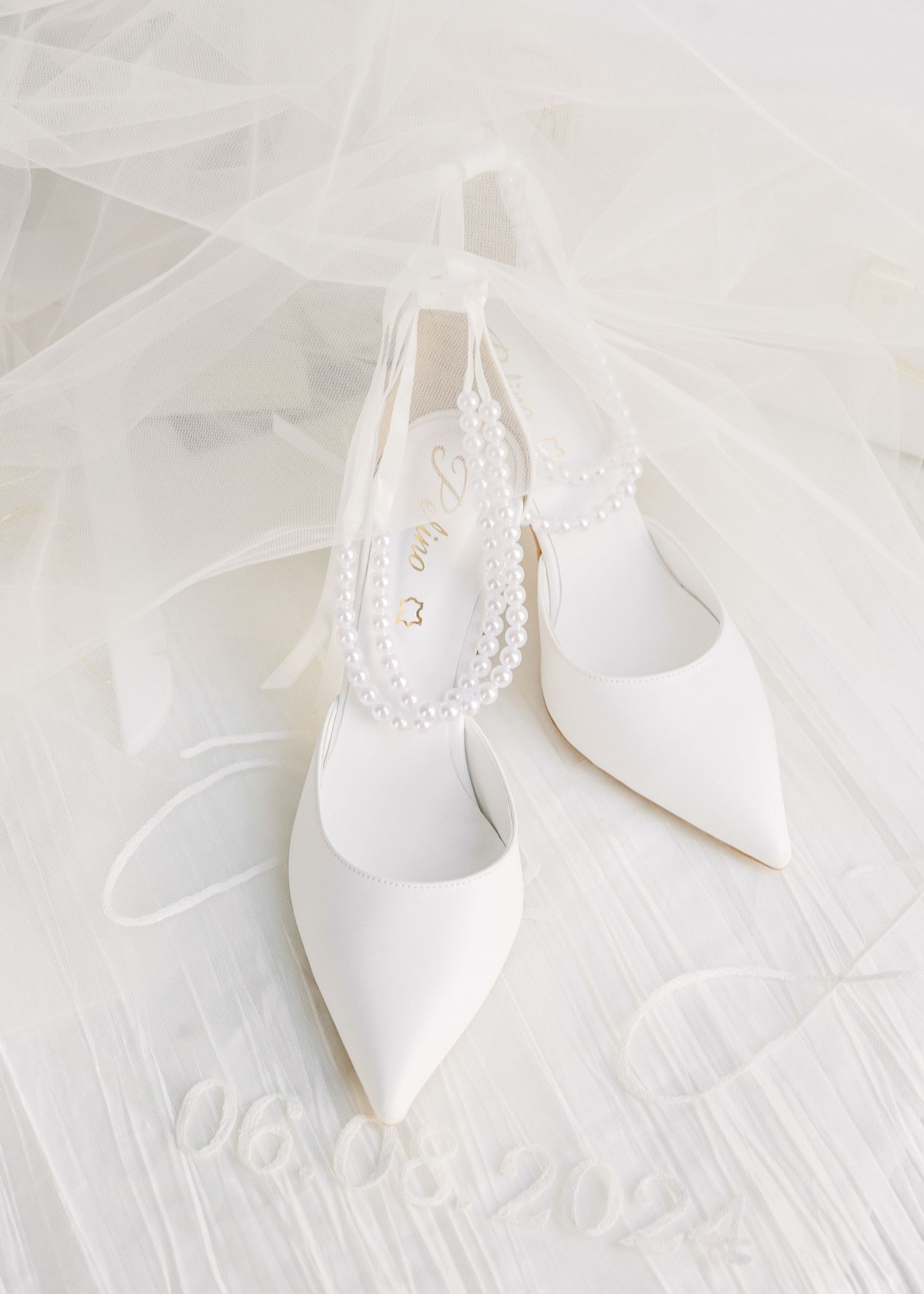 Elegant white bridal shoes with lace details displayed on a light background.