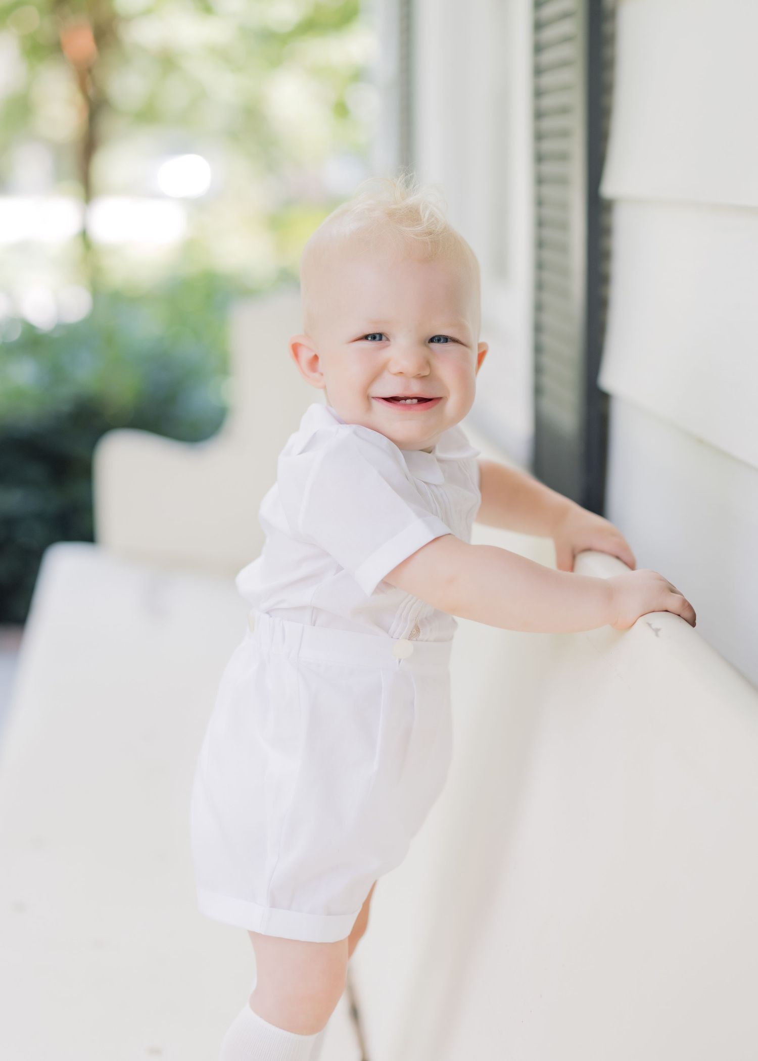 Sweet baby in white clothing laughs and plays in a bright, airy room.