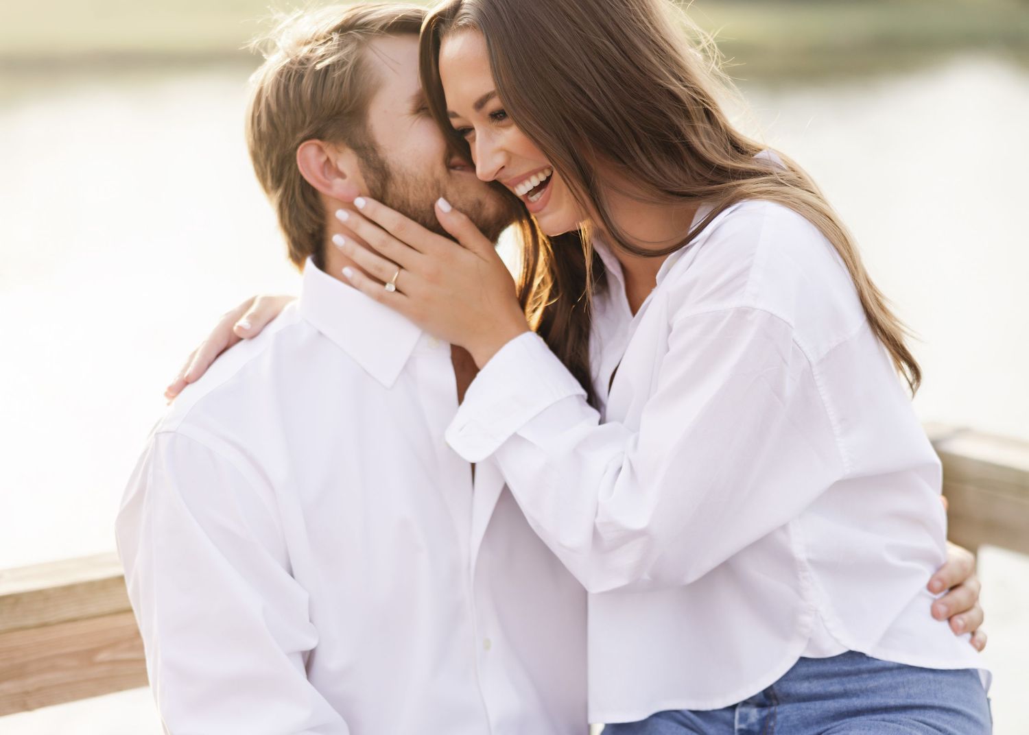 Tender embrace in matching white shirts against soft natural light.